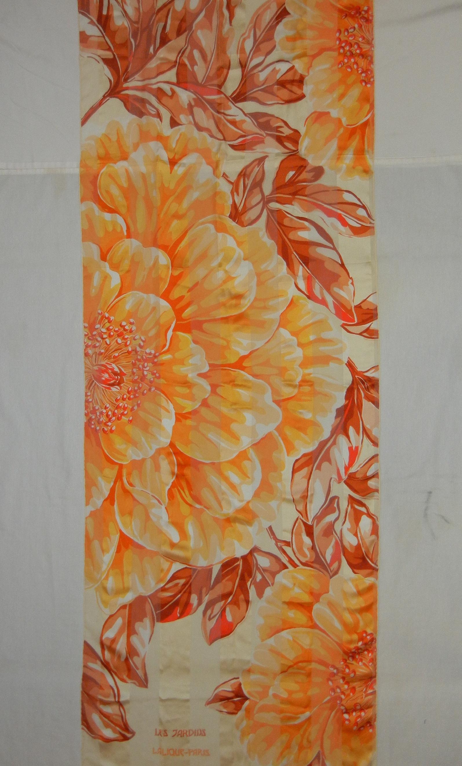 Lalique created this lovely tangerine and ivory Les Jardins see through silk rectangular scarf that can be worn as a stole/shawl on those warmer fall nights.  Large bold tangerine color flowers intertwined with copper tone leaves create a soft