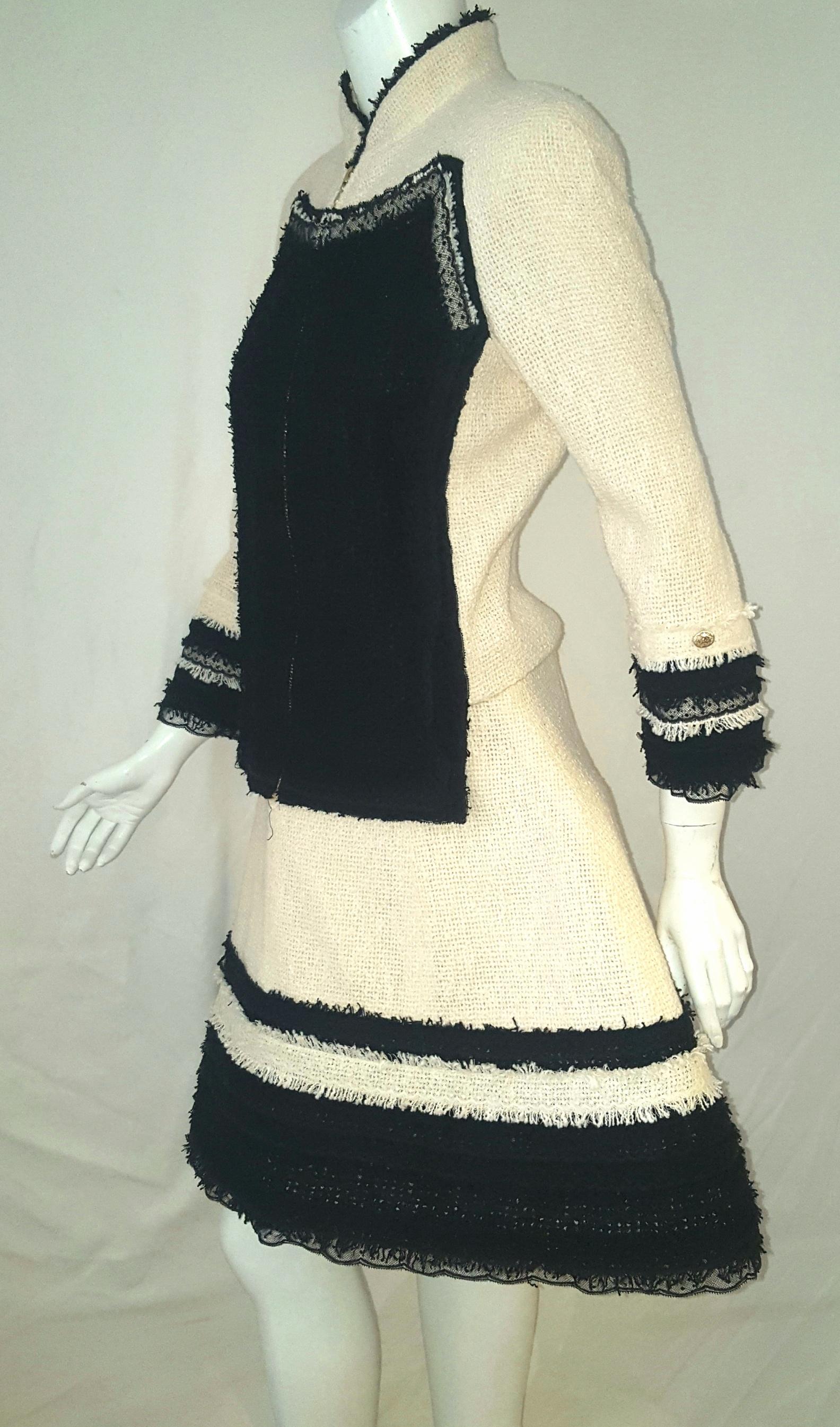Chanel ivory and black trim fringe and ruffled lace on both the jacket and skirt.  This fabulous jacket features a tailored fitted silhouette with an up collar w/ black fringe & zipper closure. 2 front plaquettes in black boucle fabric framed in