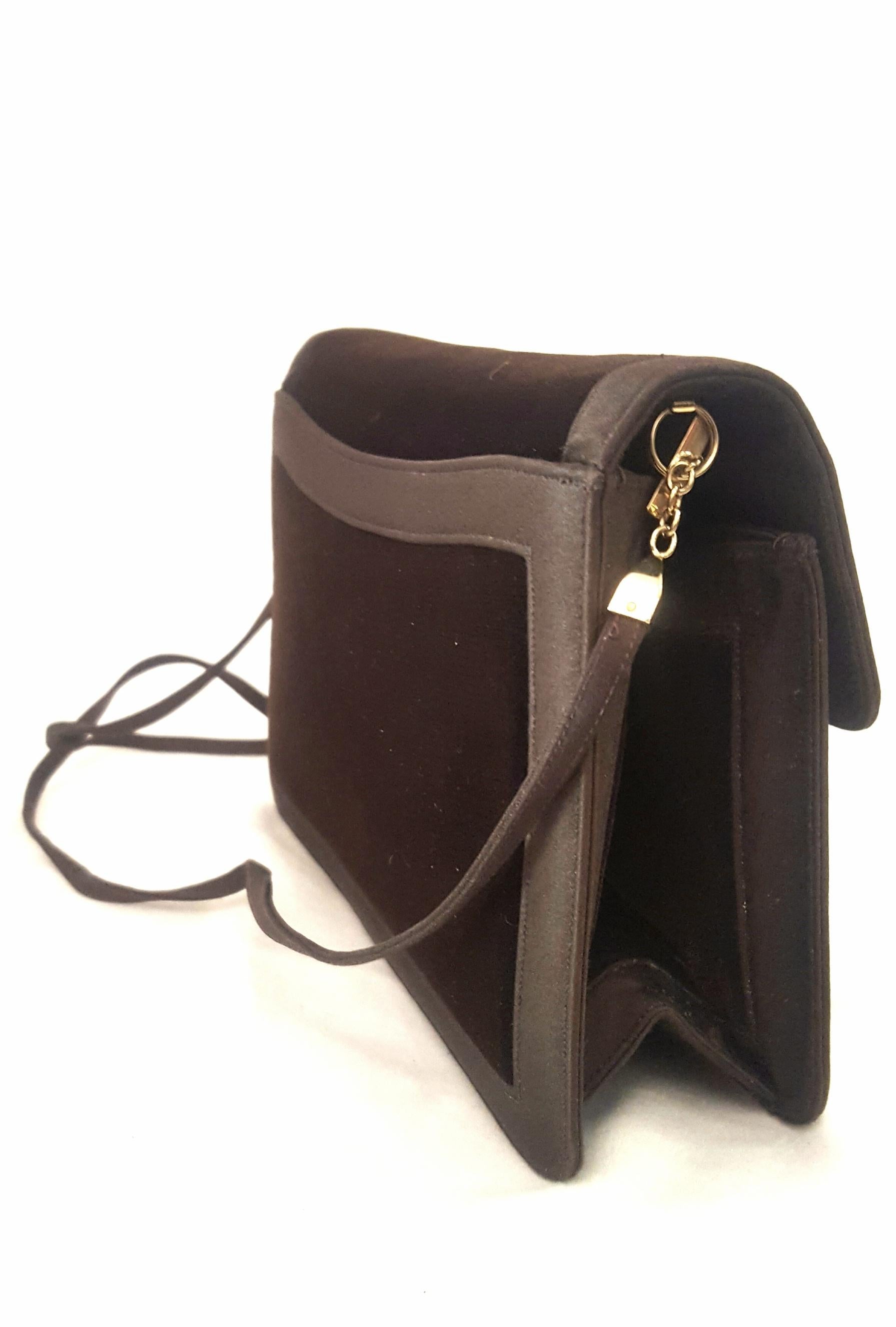 This Judith Leiber brown velvet and satin shoulder and clutch bag is lined in brown satin with one side slit pocket and one zippered pocket.  Single flap closure with magnetic snap is found at front.   This bag also contains one exterior slit pocket