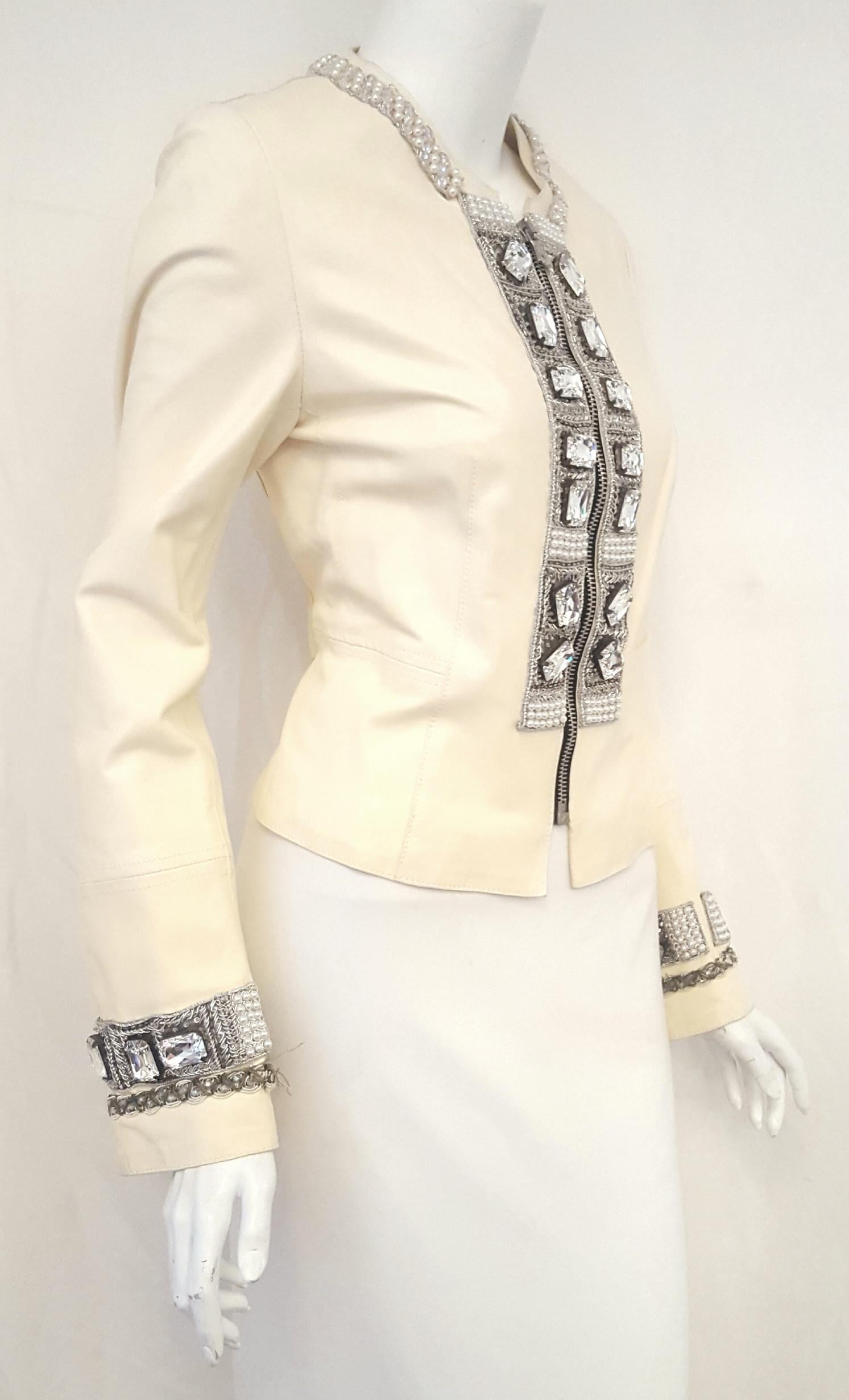 Luxurious Dolce & Gabbana ivory lambskin leather jacket is highlighted by large emerald cut, clear crystals on both sides of the front silver tone central zipper.  The same bold crystal decorations are also found around the cuffs.    Around the