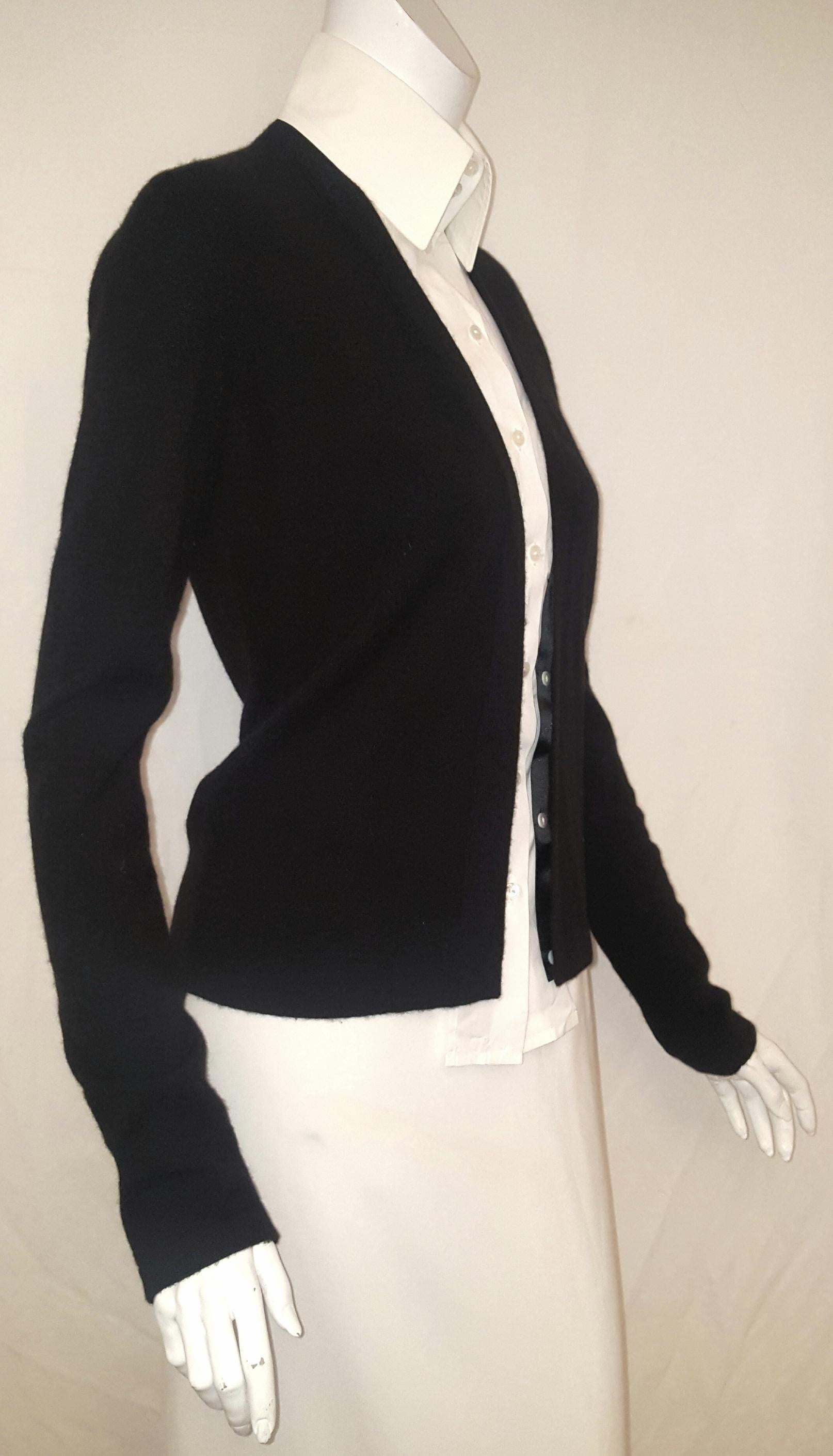 Chanel black cashmere knit cardigan has a faux insert cotton blouse that is detachable since it is only the white collar and front faux shirt that includes Chanel logo buttons.  Black and white was the color for the 2004 fall collection  and was