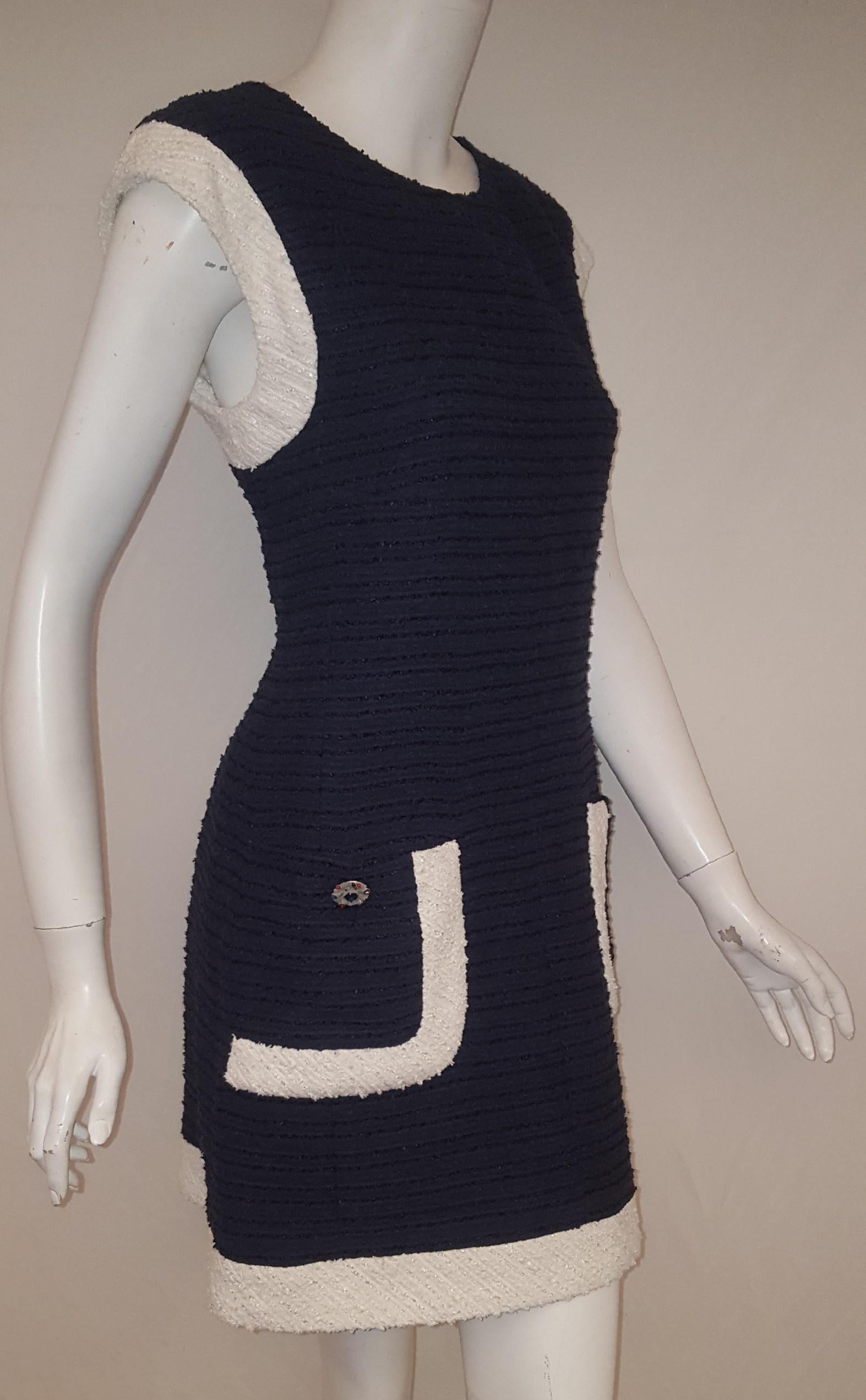 Chanel navy and white boucle sleeveless dress from the 2014 collection includes an artistic multi color gripoix button at each patch pocket.  This dress is trimmed in white boucle around arm opening, patch pocket and  at hem. For closure a hidden