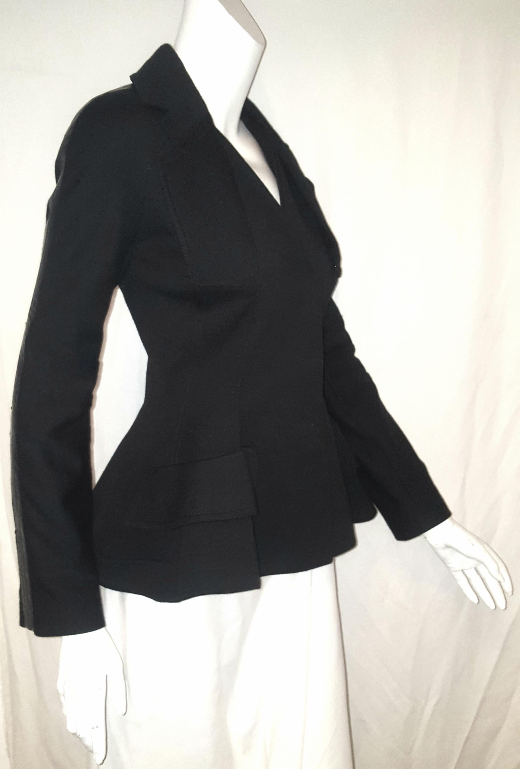 Christian Dior black wool blend jacket is styled with a faux vest insert at front.  With modified notch collar and containing 2 faux  flap pockets at front the hem is turned up and is gathered at the back vent and it comes up to the collar.  The