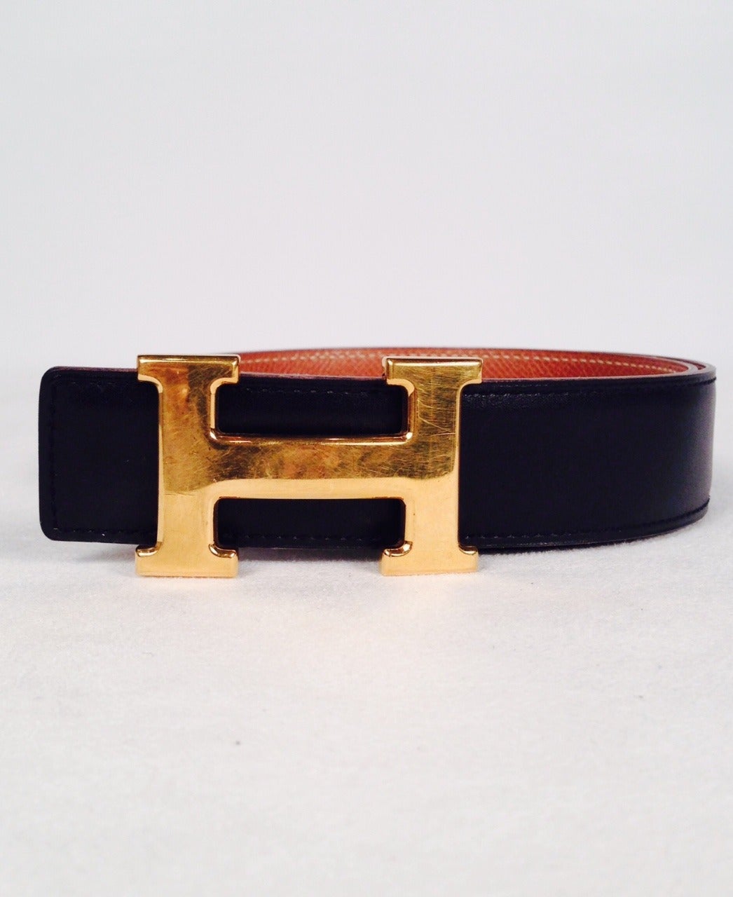 Highly coveted and collectible Hermes reversible belt with black box leather and textured gold leather.  Features over-sized brushed gold tone 