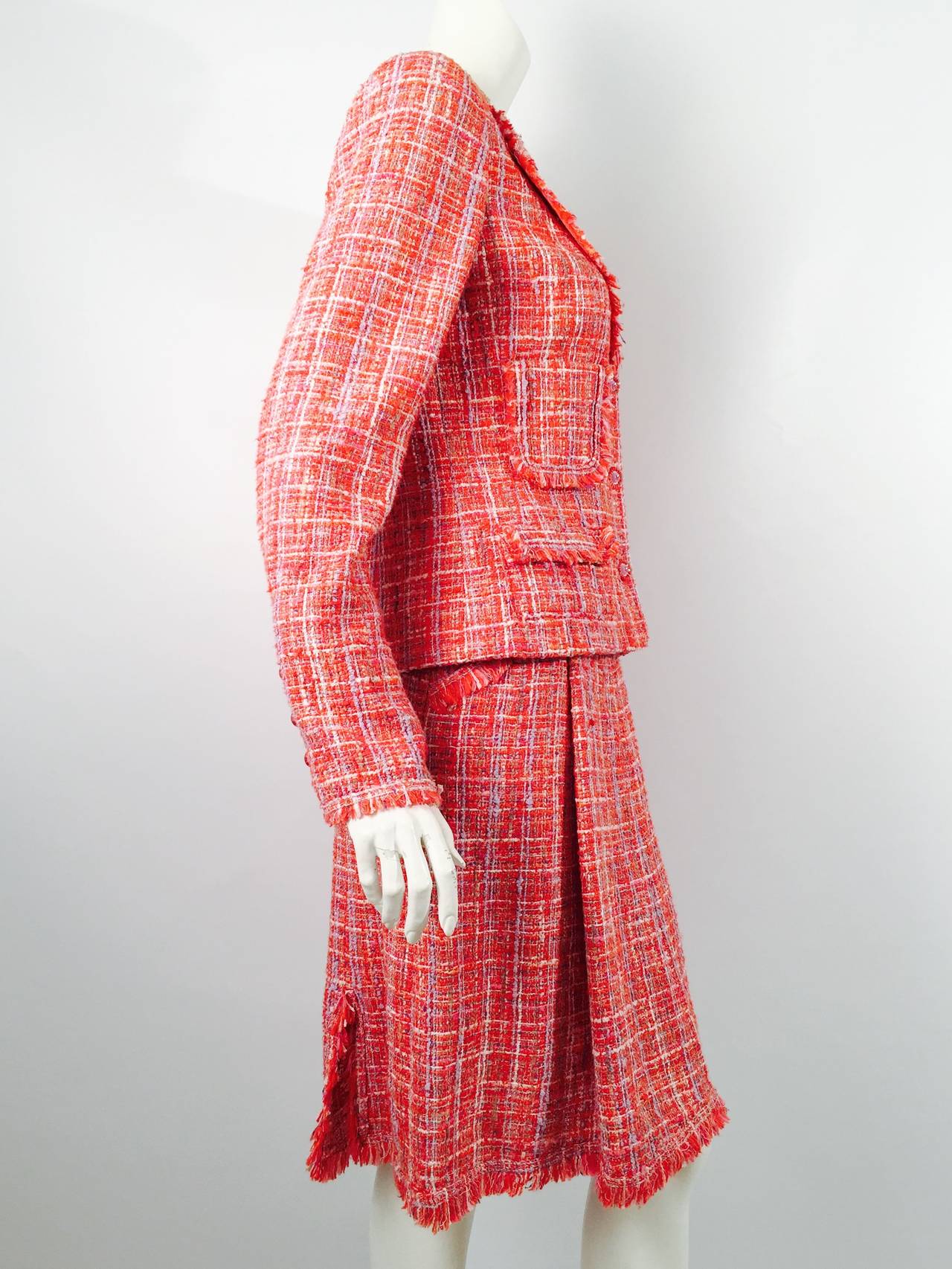 Chanel 2004 Spring Skirt Suit is true to the legend of Mademoiselle!  Primarily red cotton blend tweed is fringed at collar, cuffs, pocket flaps and skirt hem.  Skirt front has bold box pleat and three flirty back slits.  Skirt also has two front