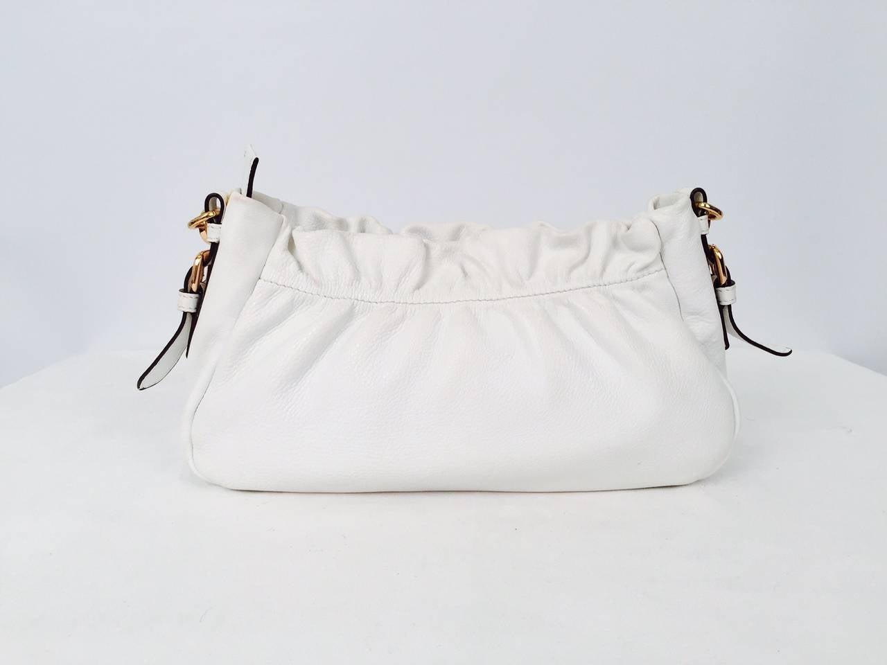 Prada White Bag with Detachable Shoulder Straps is versatility at its best!  Features ultra-luxurious grained leather and gold tone hardware.  Slightly gathered, bag has top zipper and top stitched bow on front.  Interior is lined in durable, yet