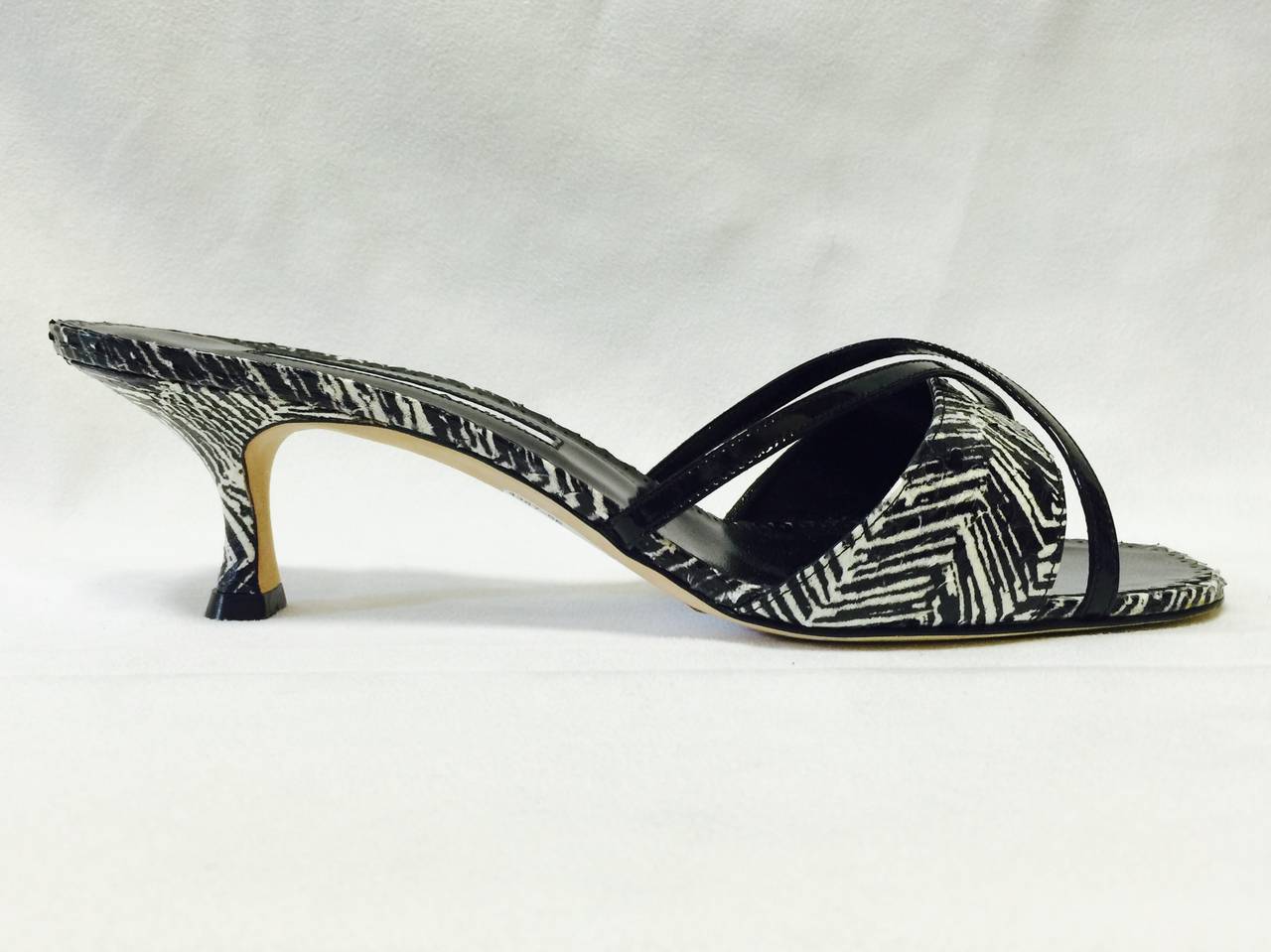 These Manolo Blahnik Mules show why this superstar shoe designer is beloved by some of the world's most influential women!  Features supple snakeskin, coy kitten heels, and paten leather cross straps.  Black and white print is reminiscent of zebra. 