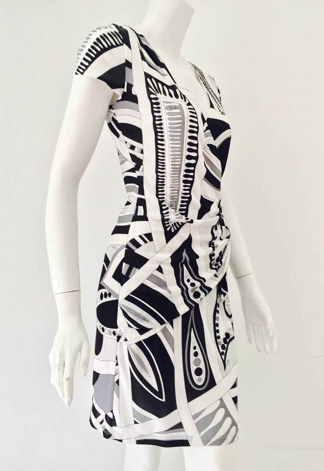 Black, Grey and White Print Cap Sleeve Sheath is quintessentially Emilio Pucci! Abstract print highlights a form-fitting, flattering design. Dress is gathered on left side at waist and right side at thigh and features sophisticated v-neckline. 