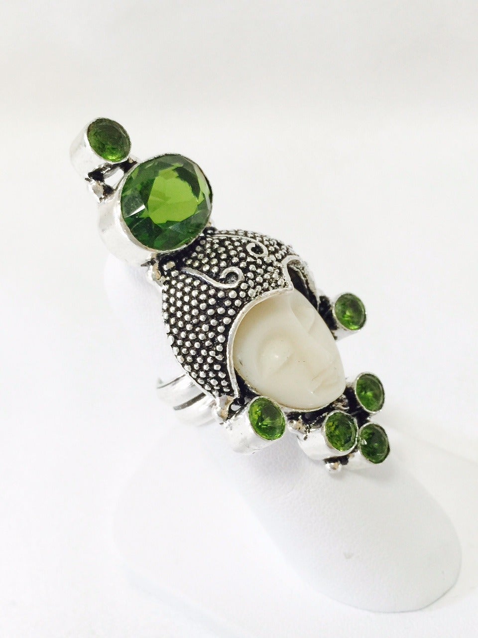 Sterling Silver Peridot Ring is graced with a most serene and mystical carved bone moon face!  Face sports a textured cap and 7 faceted Peridots.  Dramatic and unusual!  Consider wearing on your index finger...and make your point!  Size 7.
