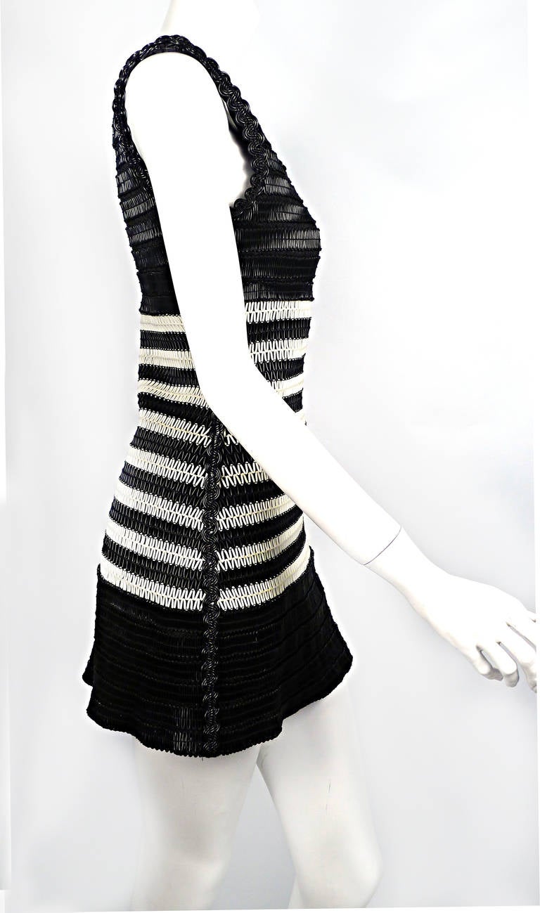 Calling all “Chanelophiles”!  Rare Chanel PVC a-line, tank dress best represents this legendary house’s commitment to modern and technologically advanced materials.  Dress features black and white horizontal looped stripes and rikrak scalloped hem
