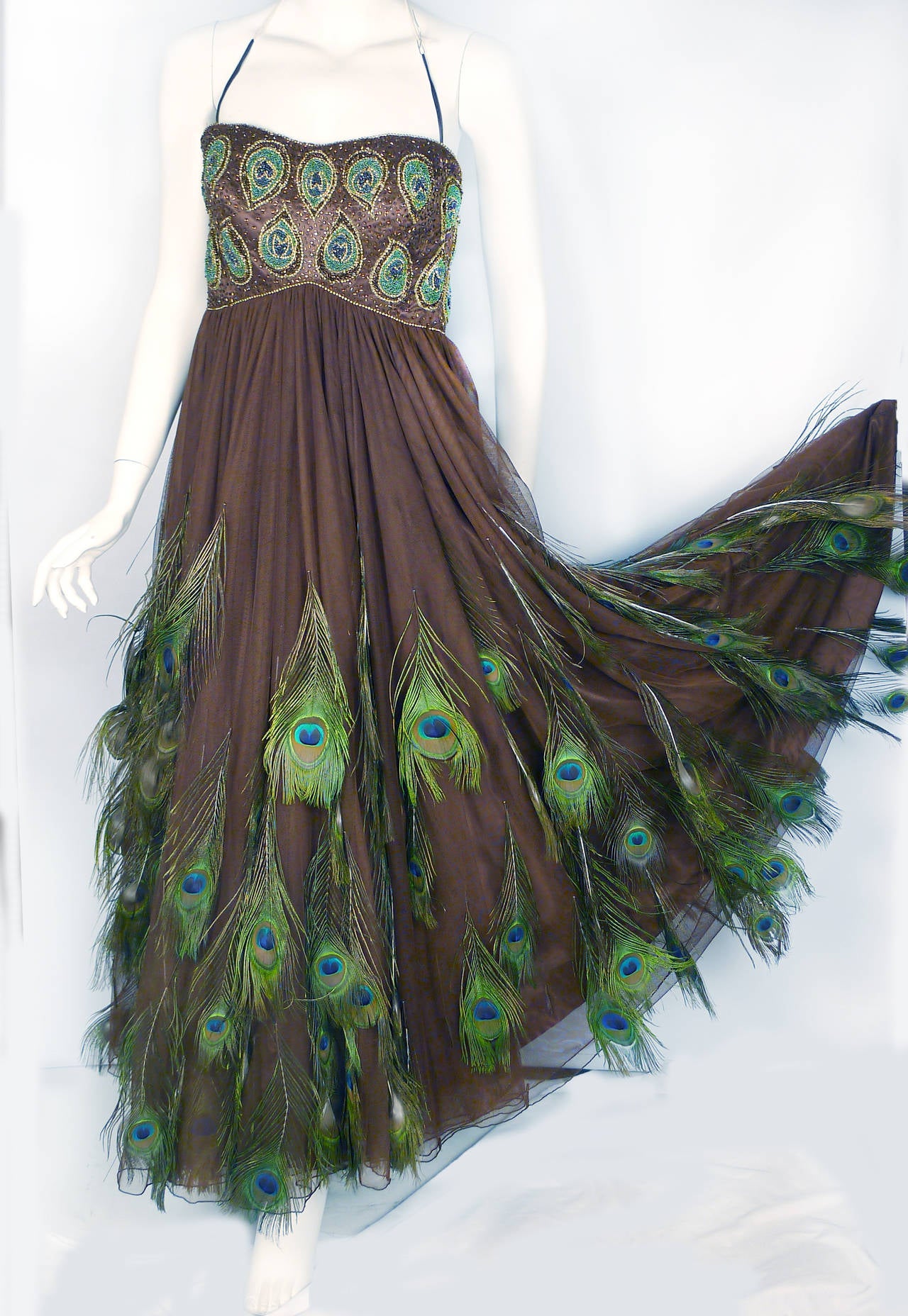 Stunning chocolate tulle evening gown over silk satin will leave your admirers breathless and in awe of your natural beauty.  Why paint the peacock?!  Gown features Empire Waist with extensive bead work on the bodice.  Authentic peacock feathers