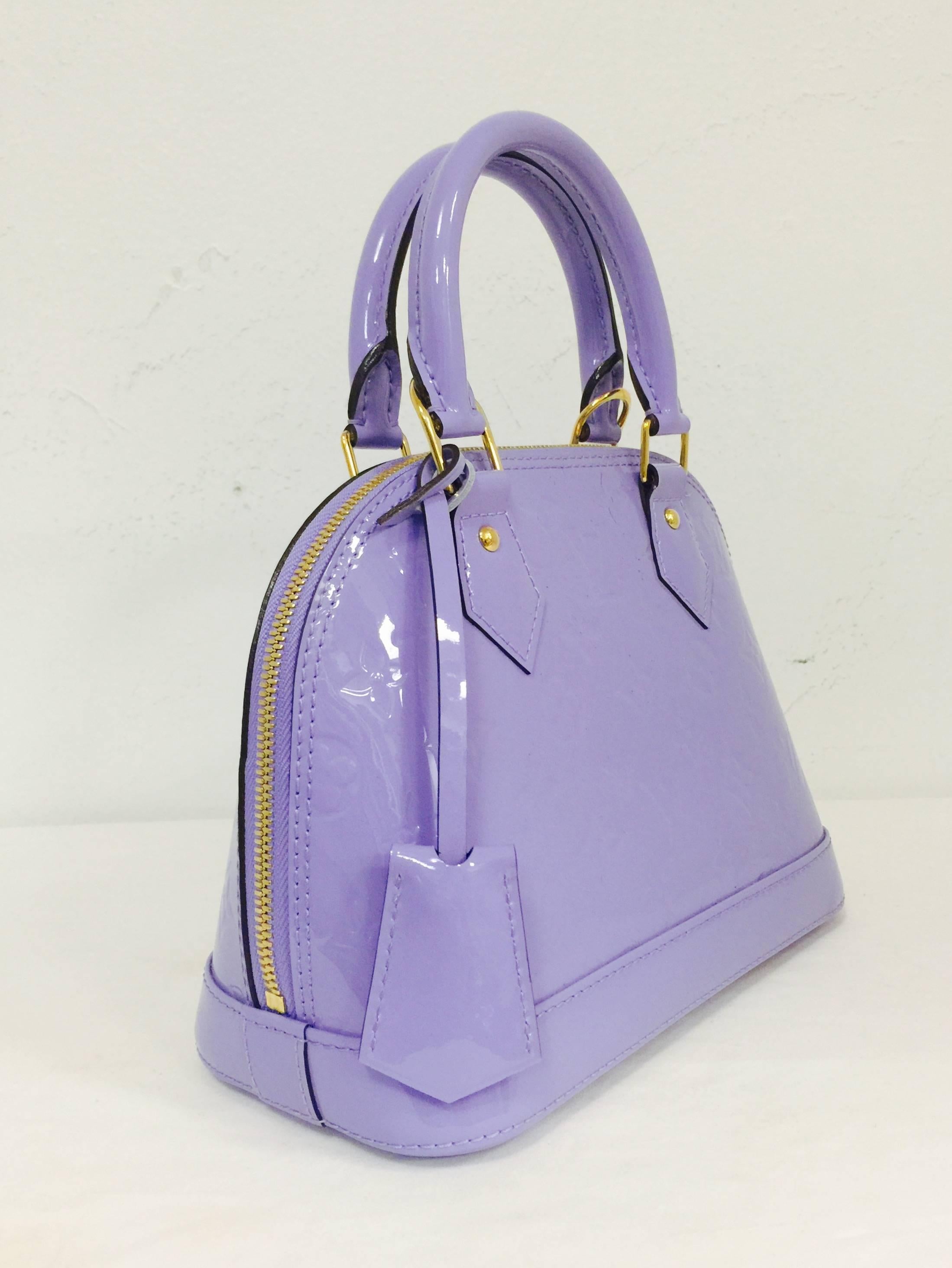 Louis Vuitton 2014 Spring Limited Edition Alma Lilias Bag is a must for any connoisseur of all things Louis!  Features the world renowned stamped patent leather (Vernis) in a luscious shade of lilac, gold tone hardware and a strap that easily