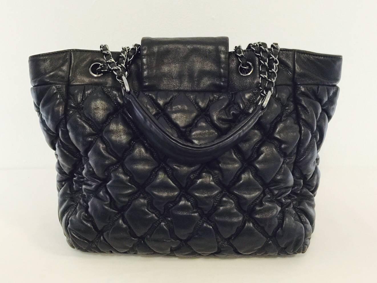 Chanel Black Tote proves that one can be practical and stylish!  Features padded signature diamond quilted lambskin, rhodium hardware, double leather-woven chain straps and smooth leather shoulder rests.  Two side pockets.   Flap snap closure