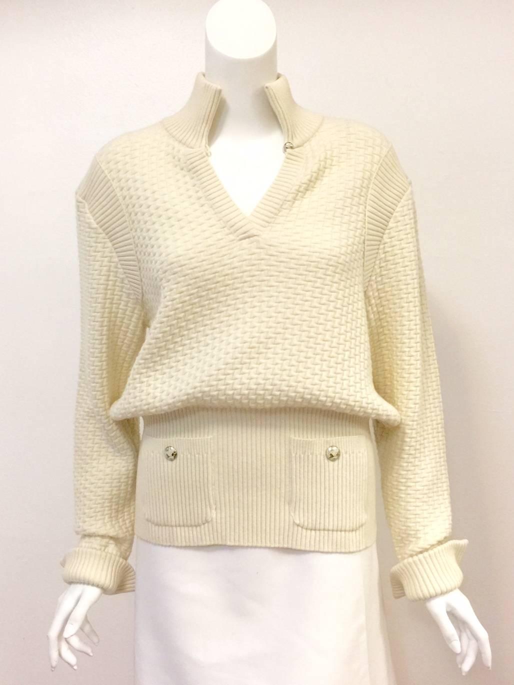 100% Ivory Wool Pullover Sweater proves that Chanel is much more than mere boucle skirt suits and quilted handbags!  V-Neckline features single button closure and stand up collar  design.  Generous proporations define the sleeves and body.  Sleeves