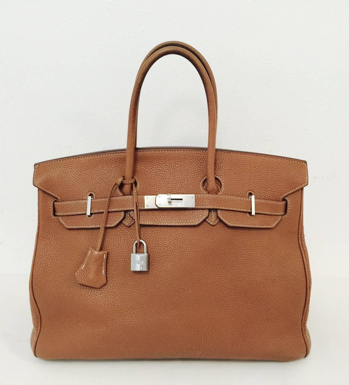 This classic, luxurious Gold Hermès Birkin 35 cm handbag is finely crafted of Clemence leather and has gold hardware. It features the intricate Birkin Croix clasp, lock and key security and Hermès' signature cousu sellier stitching. The bottom is