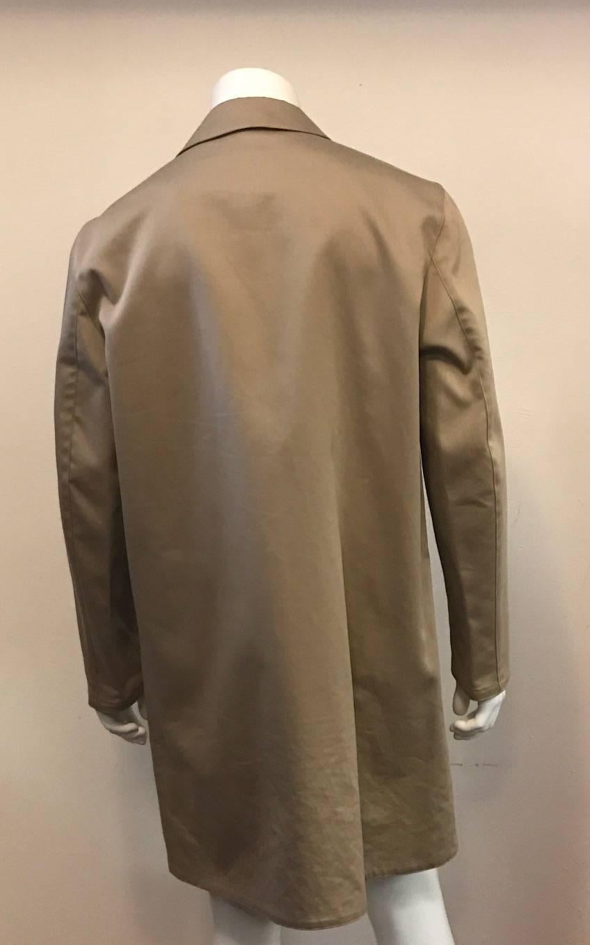 True elegance on those rainy days to cheer you up! This Hermes raincoat is 90% cotton with 10% polyurathane to keep out the rain.  The exterior is deep beige colored, with a contrasting interior in cordovan. Finished with button fastenings.   Made