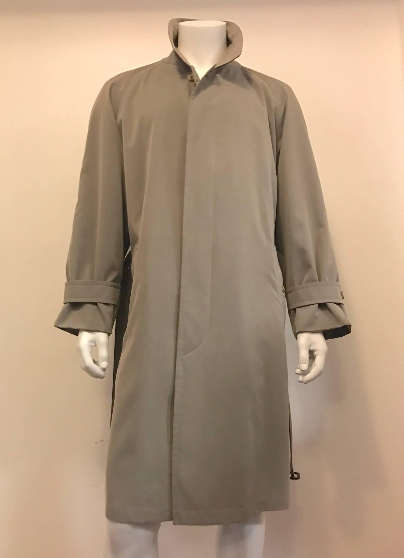 An elegant rainproof  trench coat with raglan sleeves, placket, cuff straps, a belt with leather wrapped buckle, a single vent with button closure if desired, two deep slit pockets, and one slit pocket inside.  Measures 50