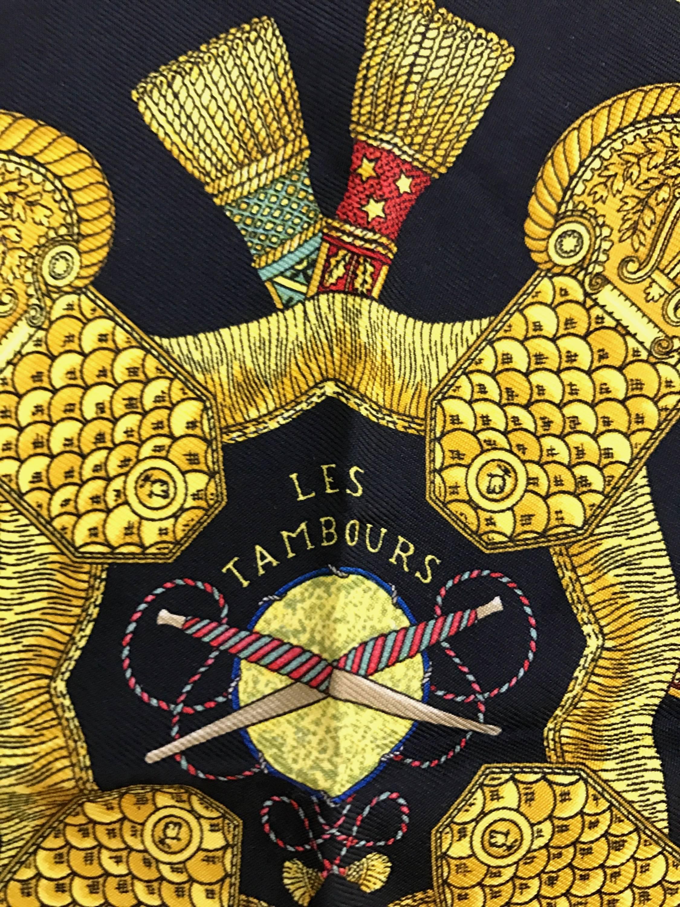 An elegant Hermes silk pocket square, vintage 1980's that shows a history of France through different military drums, representing the royal, imperial and republic eras.  In deep black, with vivid tones of reds, blues and golds.    