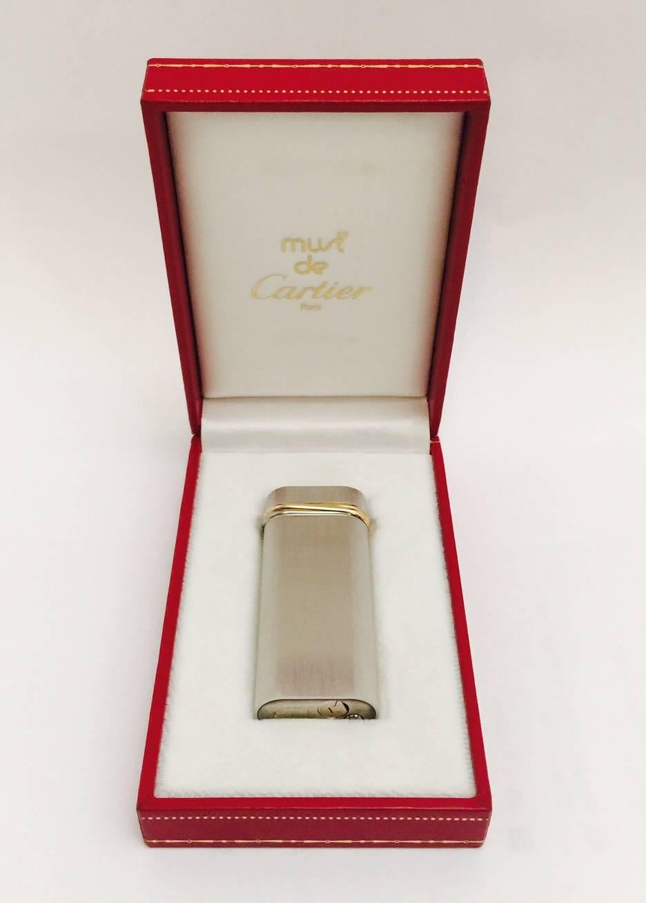 Cartier ca. 1990's Lighter in Silver Plate, Brand New in Box.  A handsome lighter, in a brushed satin finish, embellished with a gold tone band.