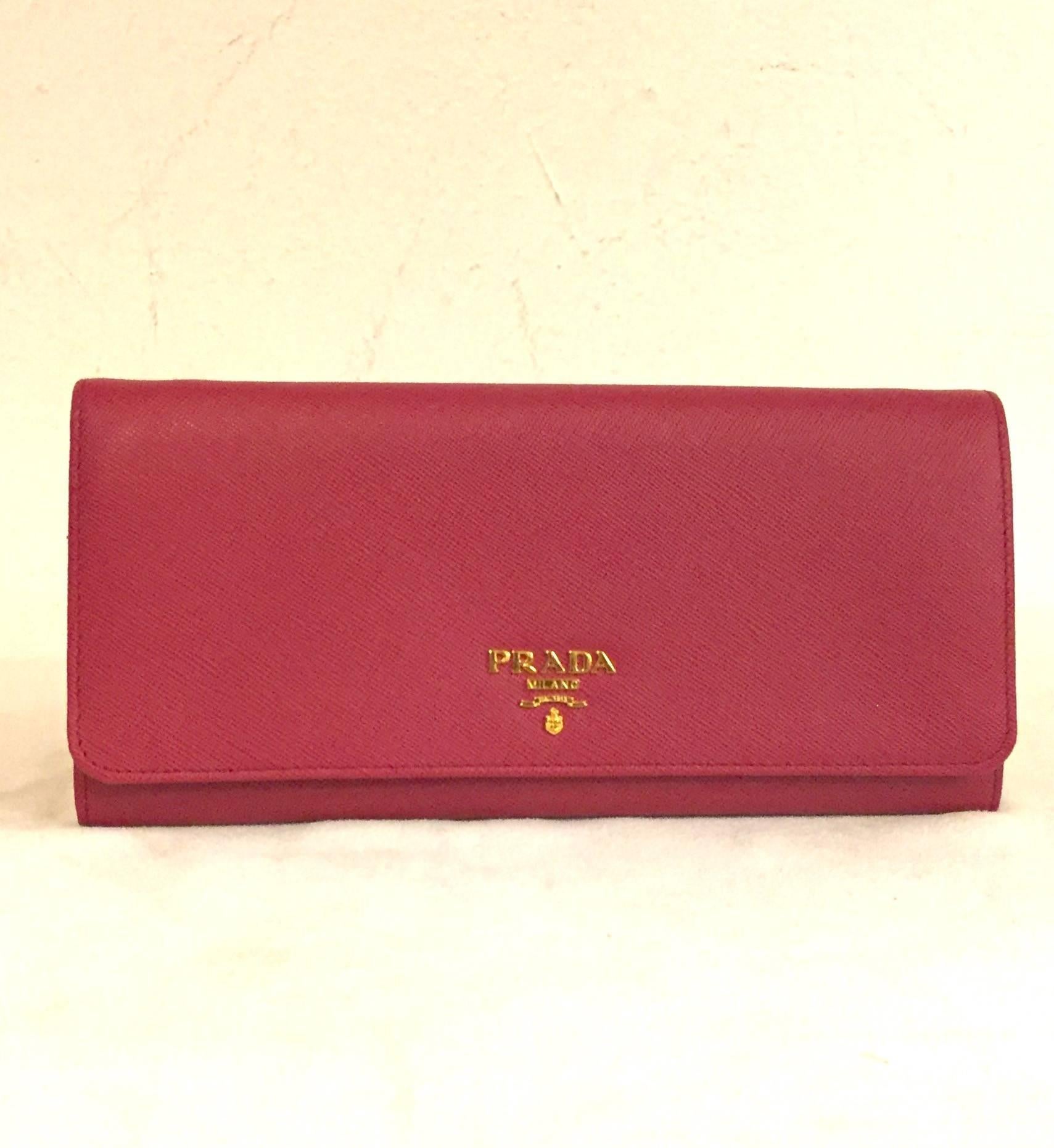 Prada Chain Crossbody Wallet is a must for travels near and far!  Features signature saffiano leather in flirtatious fuchsia, front flap and gold tone leather interwoven chain.  Snap closure reveals interior with several compartments that maintain