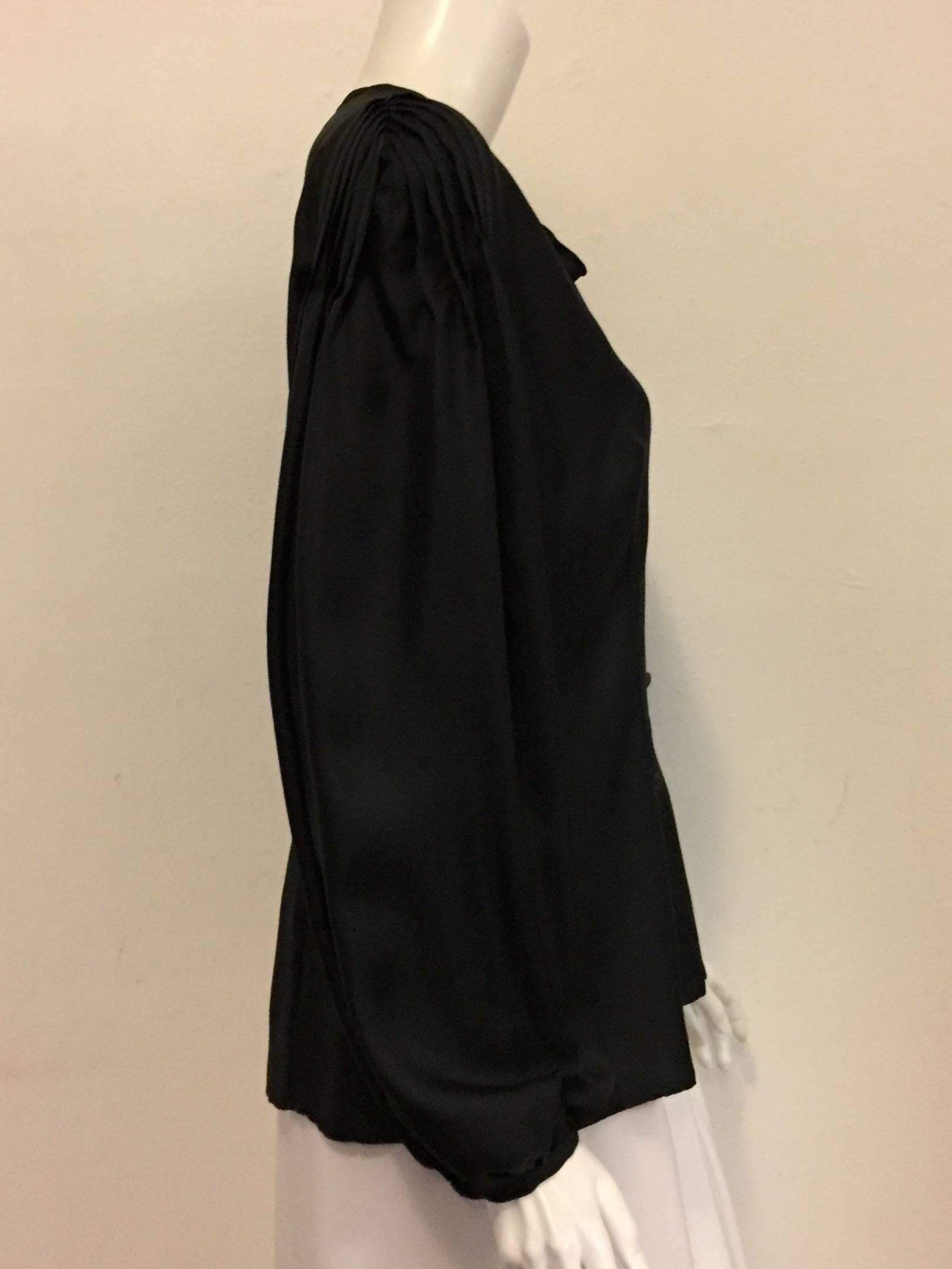 This Escada top can be characterized as the little black dress in a blouse.  Elegant and romantic, this blouse is perfect for day or night and a must for any woman's wardrobe!  Round collar with a ribbon that ties, peekaboo opening and 5 buttons