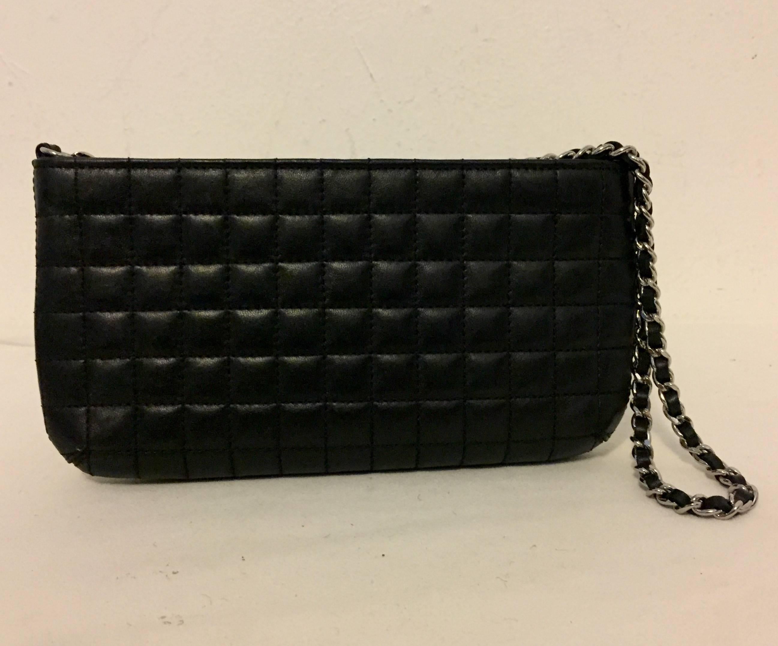 This Oh So Chic Chanel wristlet is crafted of luxurious square quilted black lambskin leather with elaborate embellishment of the entwined CC, the No. 5 and the classic Camellia flower.  The bag features a silver leather threaded wrist strap. The