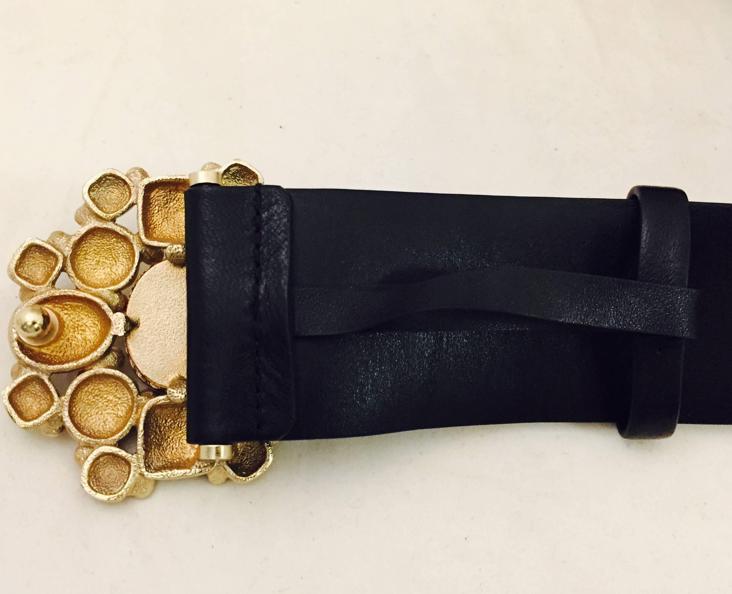 Chanel black leather belt with its eminent belt buckle medallion with Gripoix stones on antiqued gold tone flower design.  This stunner is a work of art that is wearable and unique.  The Gripoix stones are Red, Black and Blue with the CC logo on the