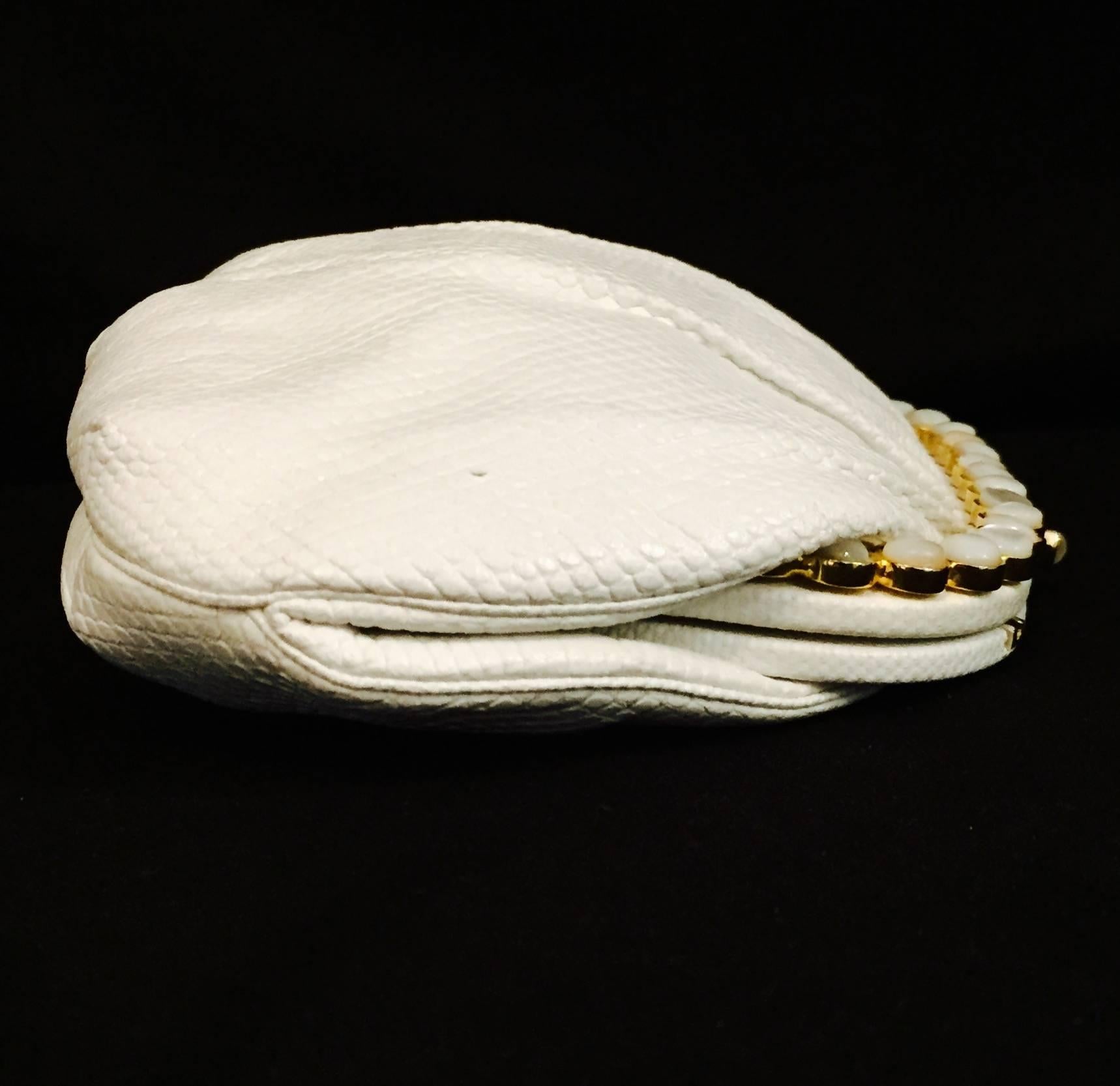 This white Karung clutch by Judith Leiber goes from day to night. It is gathered at top and the frame is covered with same lizard skin and white mother of pearl stones are set in gold tone hardware.  Hidden narrow gold tone chain strap converts the