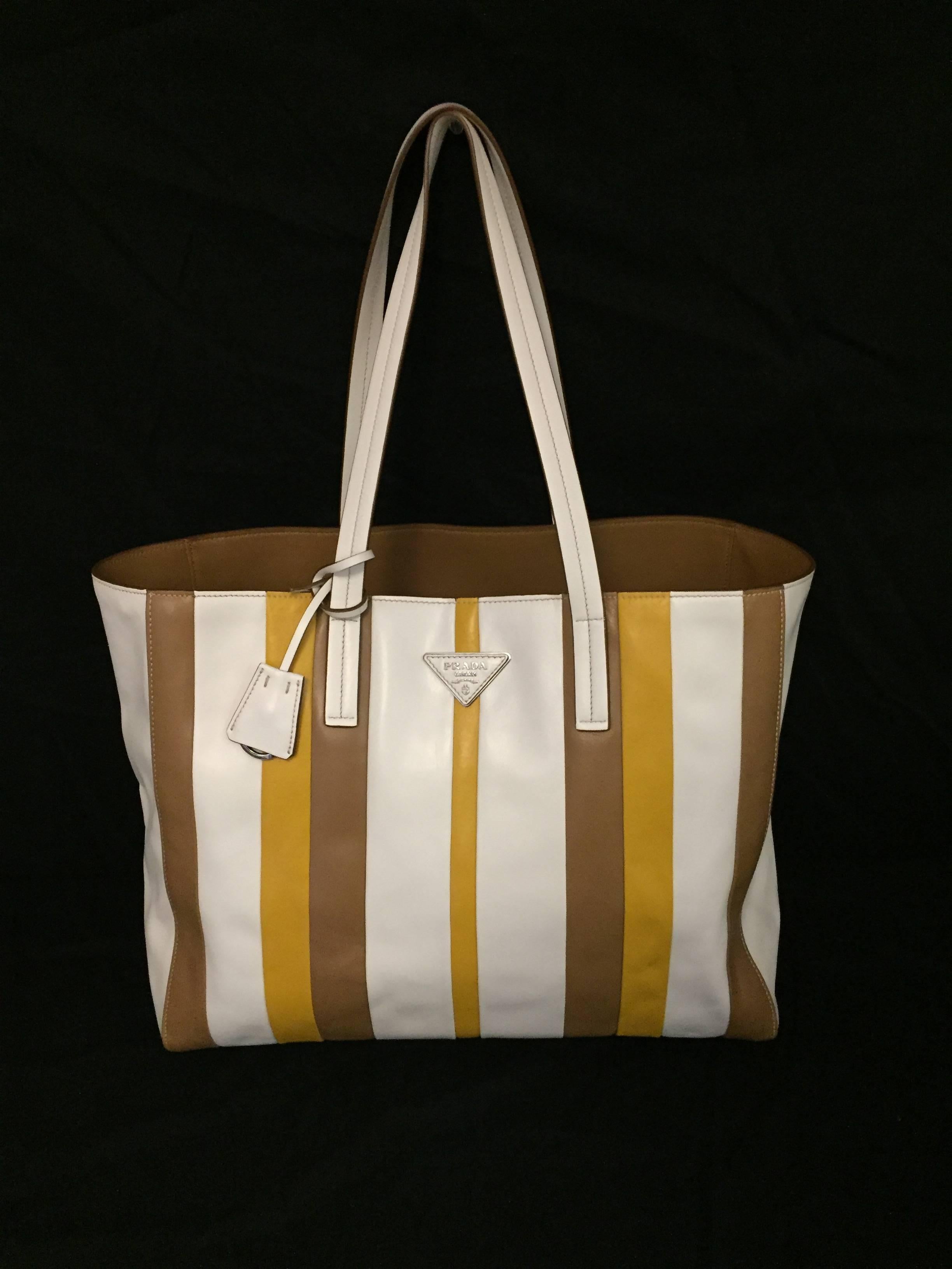 This Prada shopping tote is a must for Spring!  Features exquisite Calf Baiadera leather, flat handles, and open top.  Sophisticated, alternating white, caramel and dijon strips on front and back illustrate elevated Italian craftsmanship.  Interior