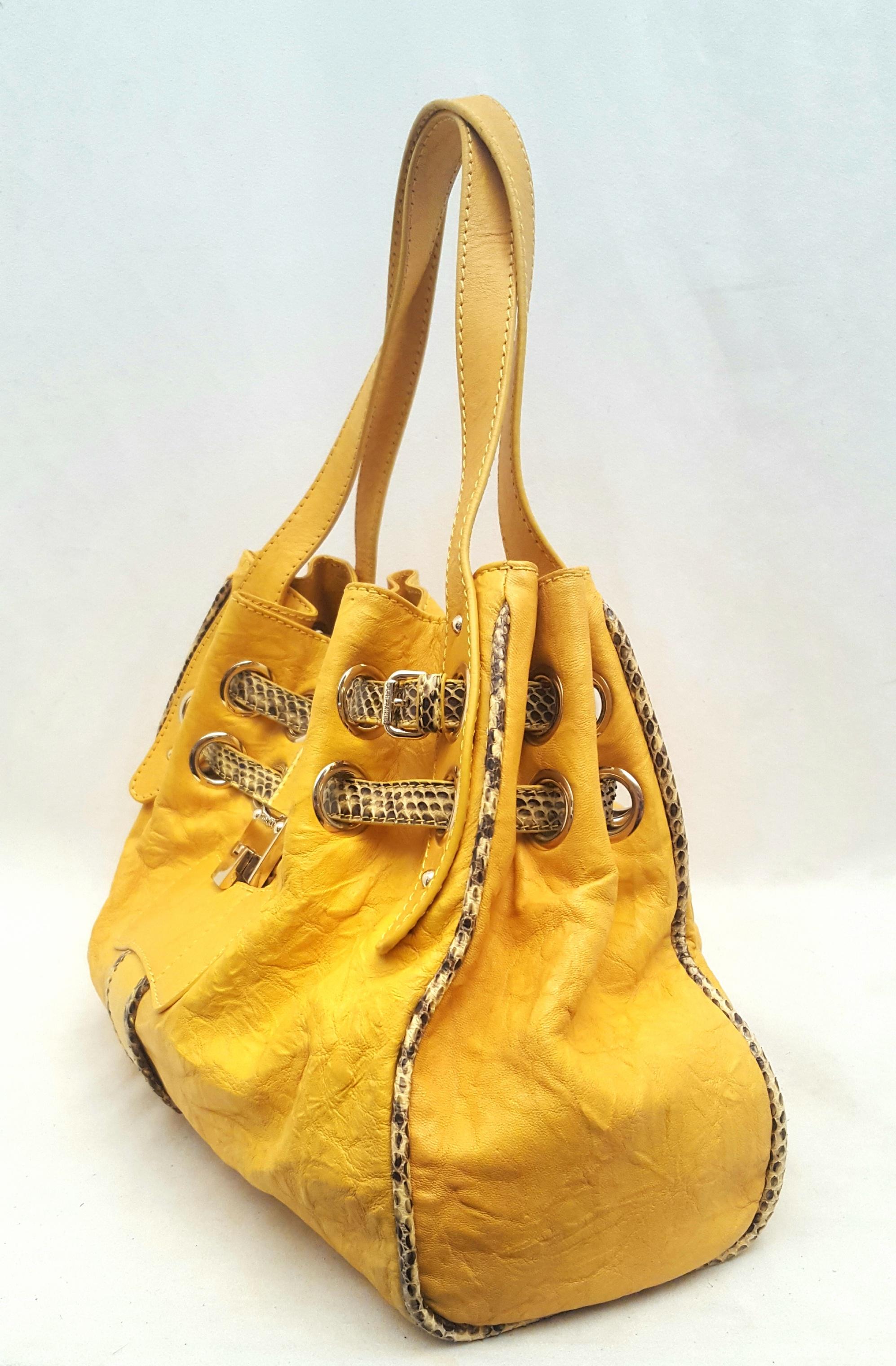 Jimmy Choo yellow leather Riki bag with brown and ivory authentic snakeskin trim details creates with the gold tone grommets a drawstring design around the top of bag.  The main center pocket is lined in tan micro suede that includes four interior