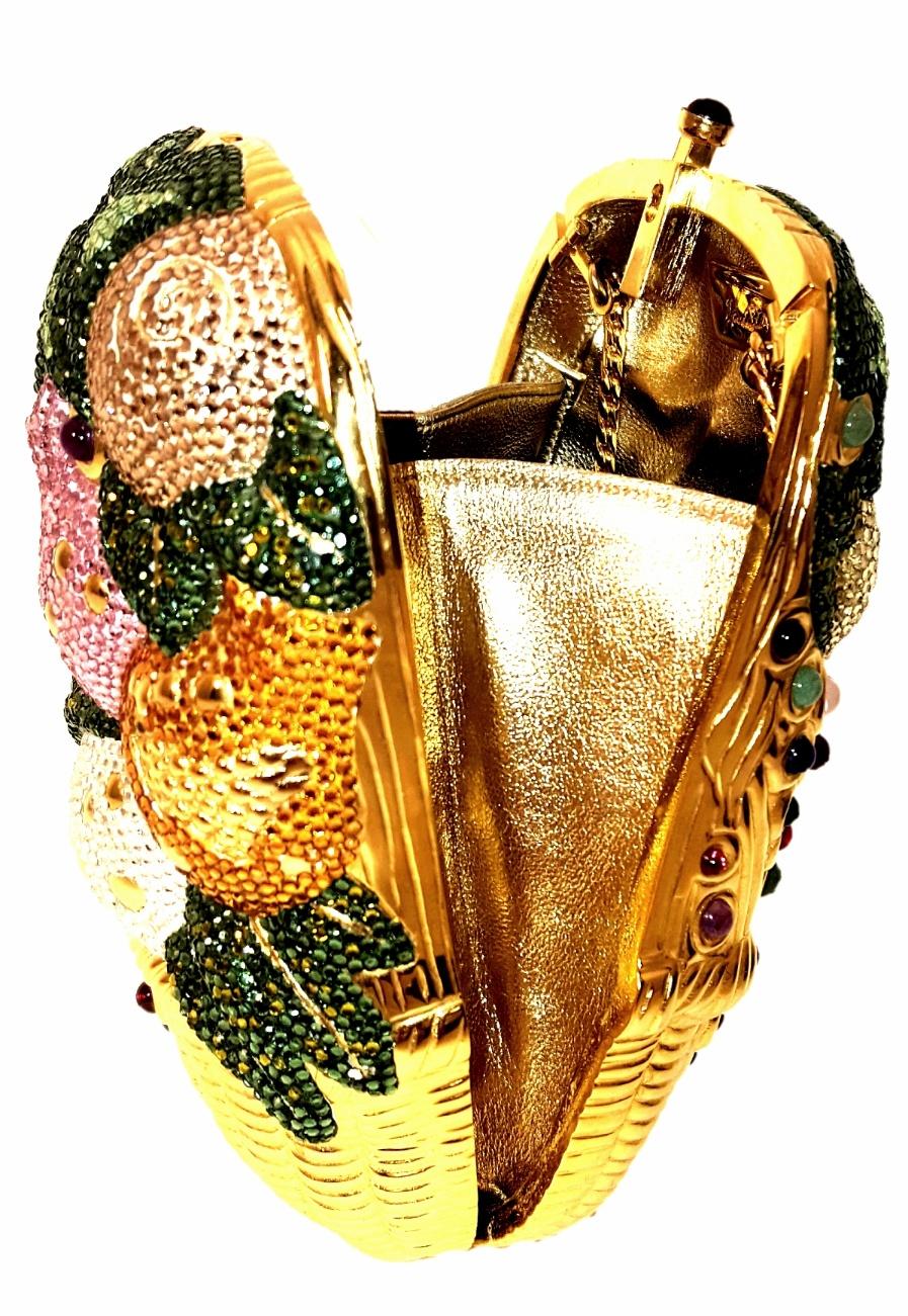 Judith Leiber crystal fruit basket clutch containing several fruits displayed in a gold tone woven basket.  The fruits, such as, pears, apples, limes and lemons are detailed in colorful crystals in pink, green, orange, lime and yellow.   To