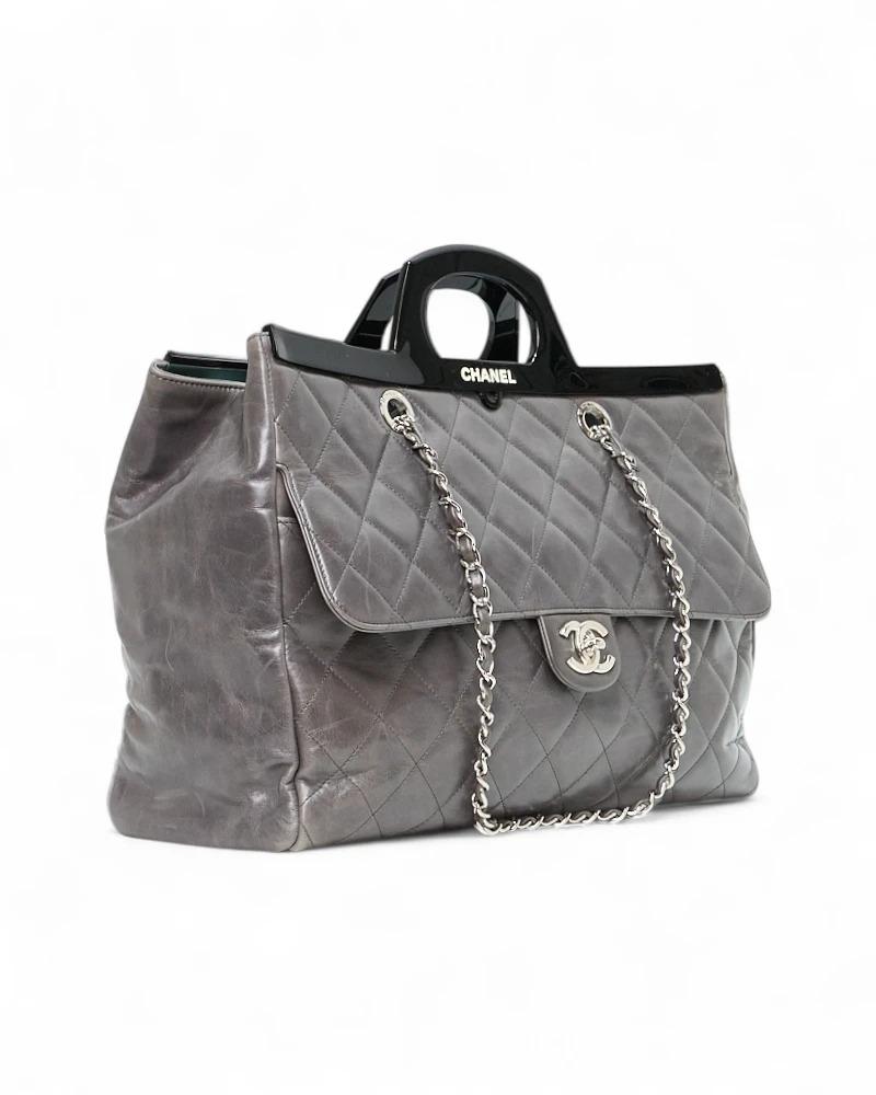 Borsa firmata Chanel, Modello Delivery Tote nella misura large, realizzata in pelle trapuntata grigia con rifiniture nere e hardware argento. Dotata di una chiusura a bottone calamitato, internamente rivestita in tela nera con comode tasche, la