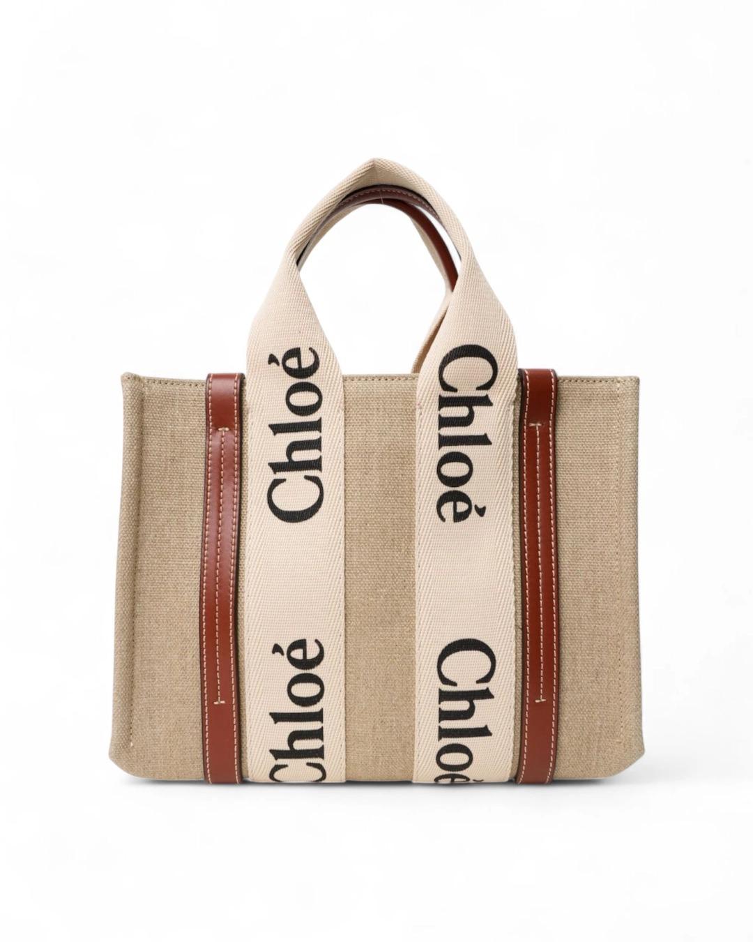 Borsa firmata Chloé, Modello Tote Woody nella misura small, realizzata in lino beige con inserti in pelle marrone. Non è dotata di nessuna chiusura, internamente rivestita in lino tono su tono con piccola tasca, la borsa è abbastanza capiente.