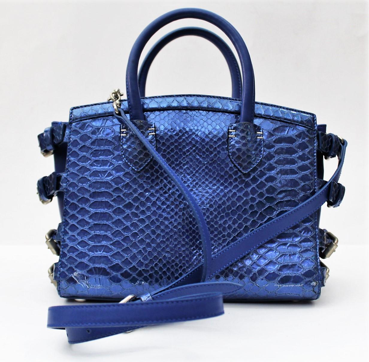 Giuseppe Zanotti G17 bag. Python patterned leather fabric in electric blue color.
Logo in metal and silver finishes. Double leather handle. Made of three internal compartments,
and one outside. Lined internally in fabric, with spotted pocket.This