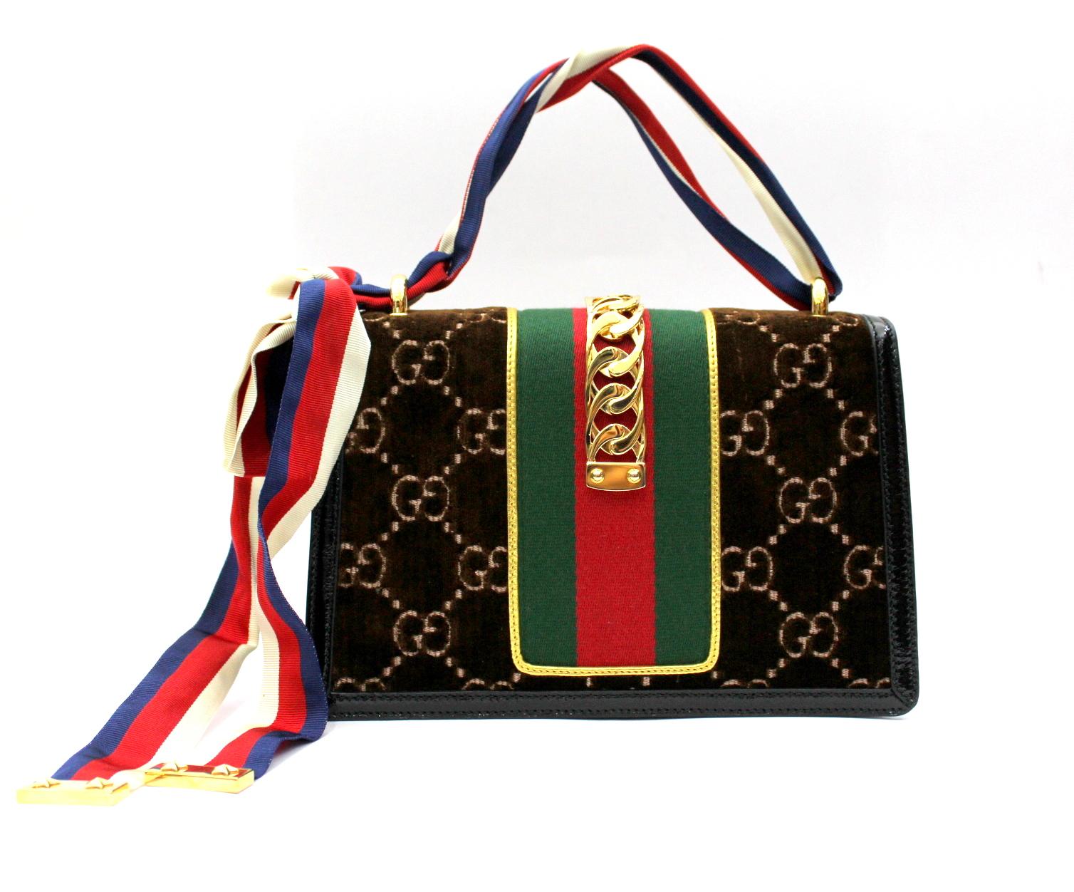 Gucci Sylvie in brown GG velvet with black patent leather trim. Green and red web style. Shiny gold-colored finish. Web in nylon with metal chain and buckle closure. Inside zipper and pockets for smartphones. Detachable leather shoulder strap,