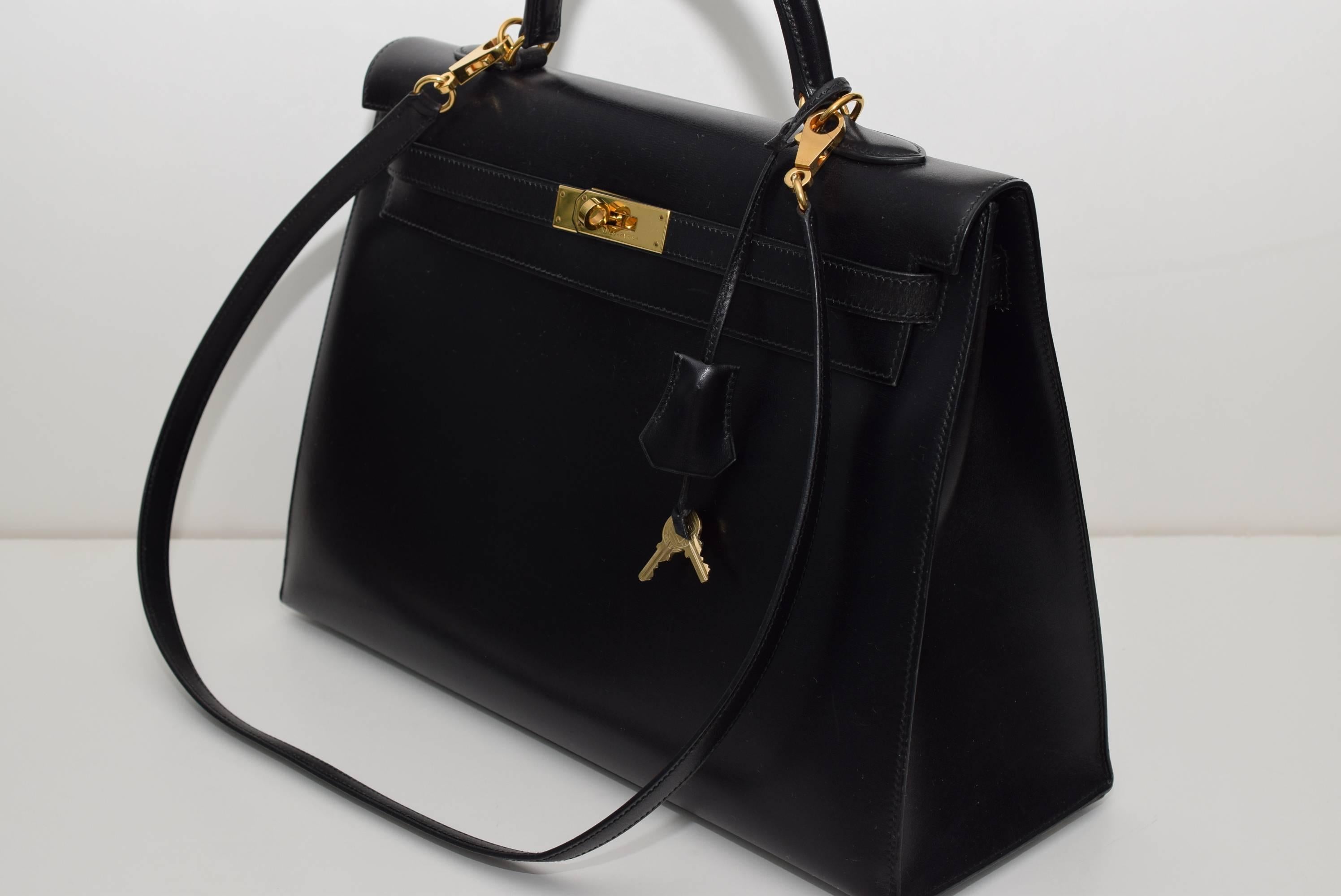 Herrmes Black Kelly 35cm in box leather with gold hardware.
This Kelly features tonal stitching, front toggle closure, lock and two keys, Hermes Box, Hermes dust bag, and a single rolled handle. The interior is lined in Black chevre and features