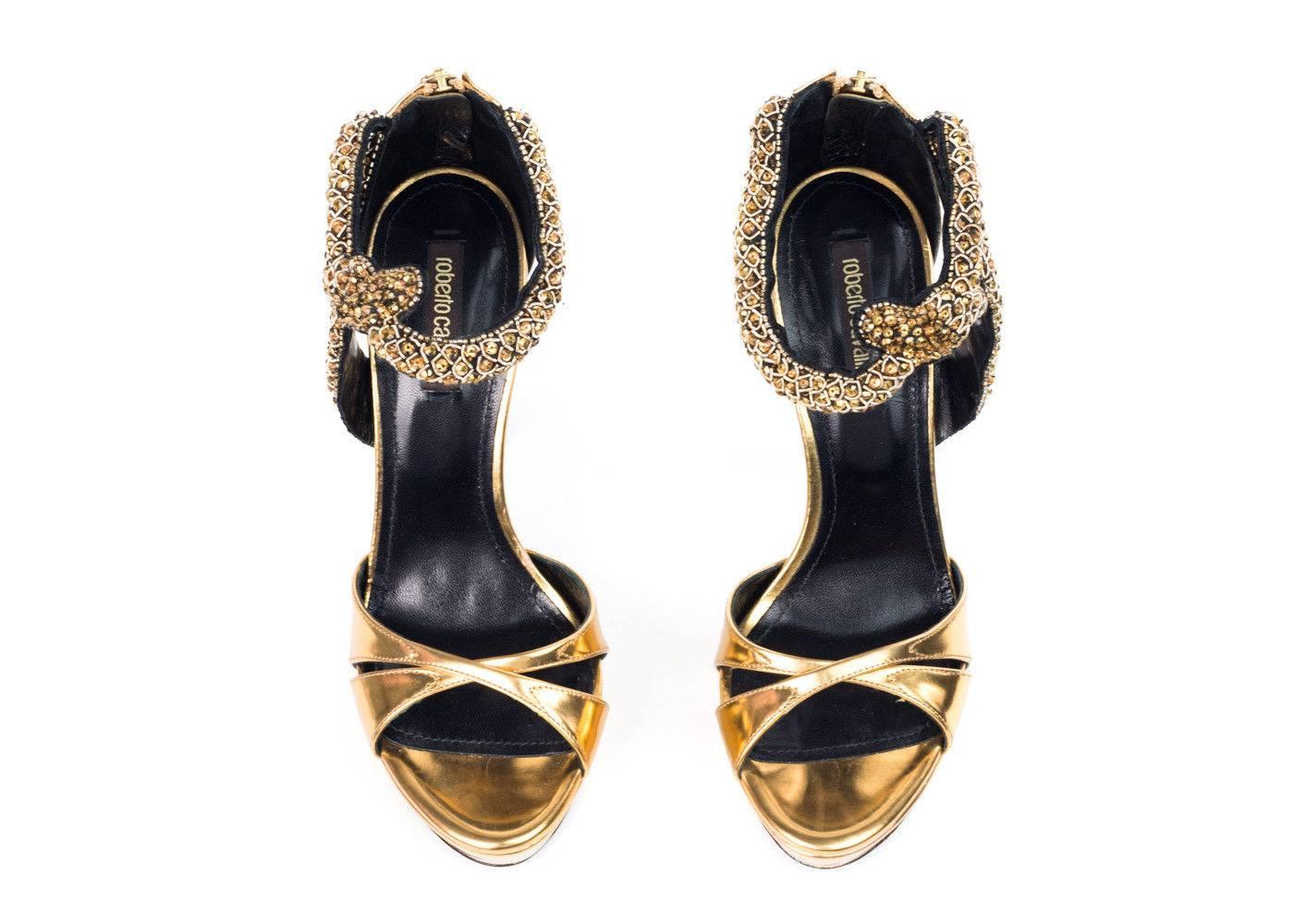 Roberto Cavalli's luxurious gold sandals feature criss-cross detail in the front, embellished ankle strap, and a gold zipper in the back.  These sandals are perfect for formal and special occasions. Pair them with a white flow dress for Grecian