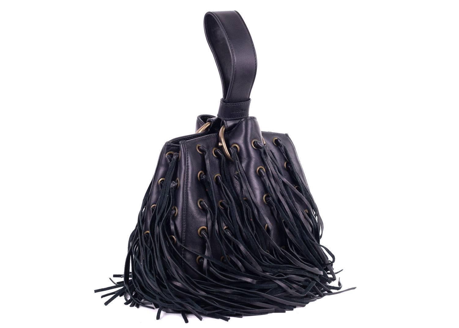 Roberto Cavalli black leather wristlet bucket bag. This bag features eyelet patterns with fringe detailing and a wristlet. Perfect summer bag, this bag can be paired with dark wash shorts or denimm with a floral top and sandals for this bag to
