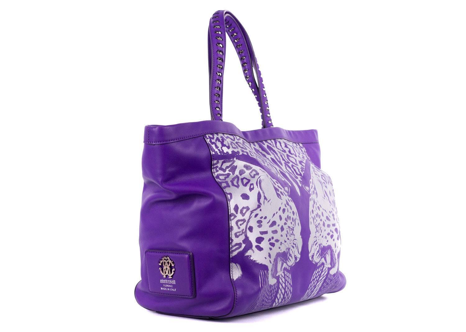 Roberto Cavalli purple leather tote bag. This tote bag features a silver metallic print with a tiger head and cheetah prints on top. This tote bag is perfect for some color in your wardrobe and this incoming summer season. Pair it with all white