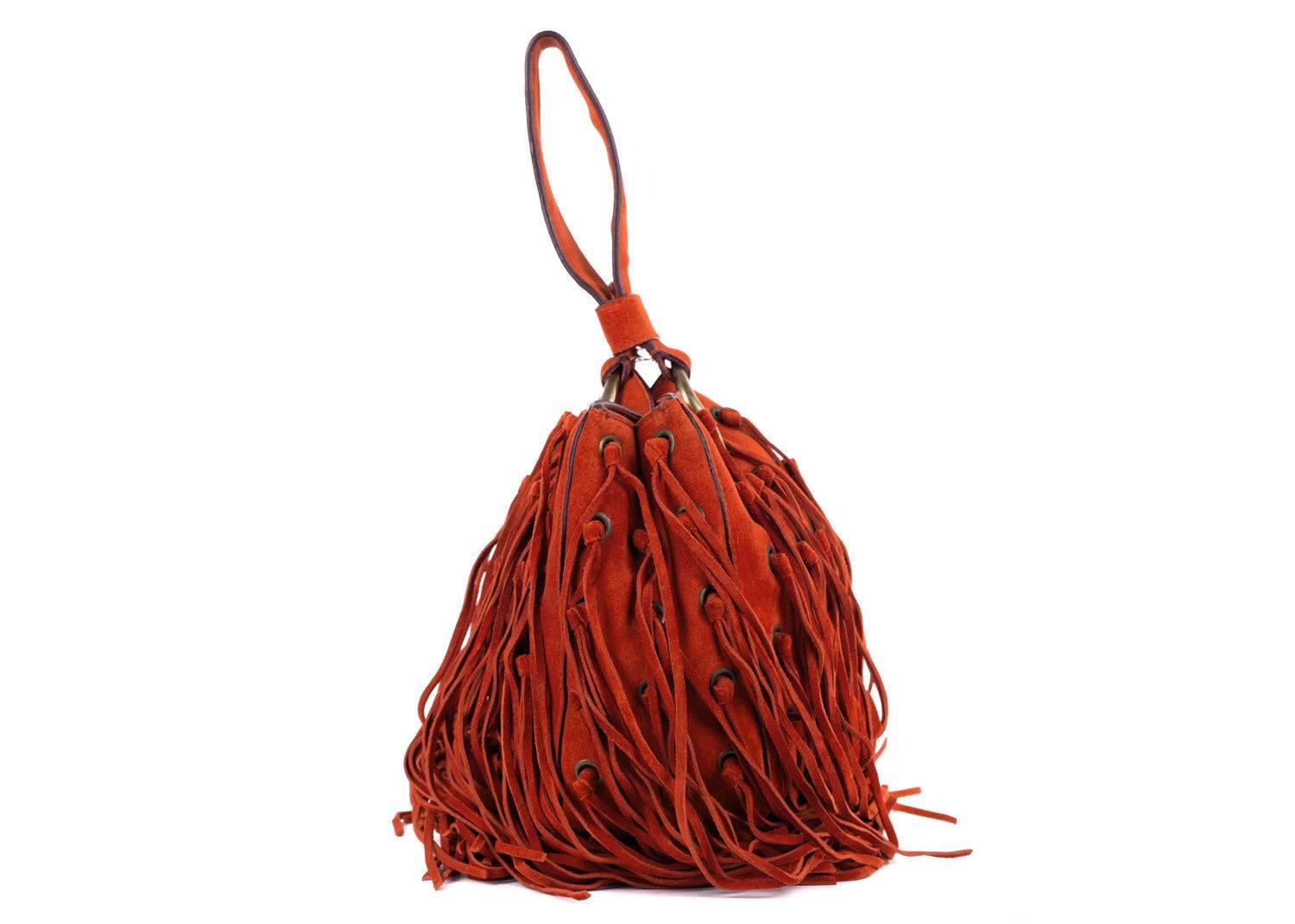Roberto Cavalli orange suede wristlet bucket bag. This bag features eyelet patterns with fringe detailing and a wristlet. Perfect summer bag, this bag can be paired with dark wash shorts or denimm with a floral top and sandals for this bag to pop.

