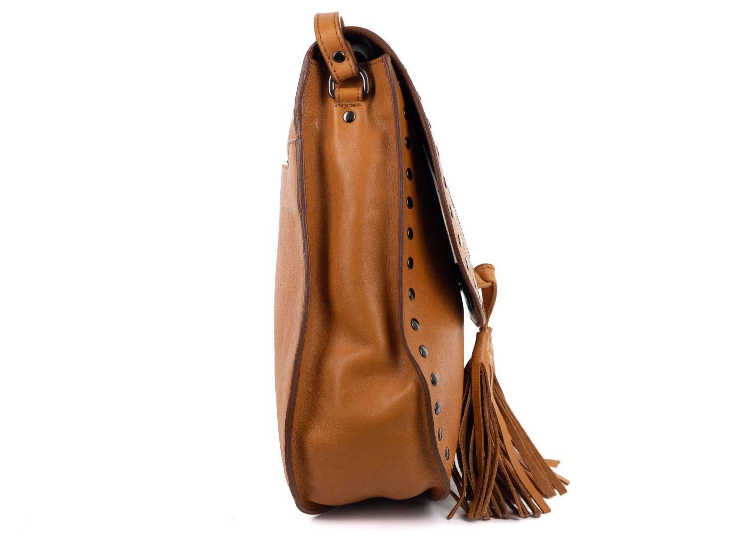 Roberto Cavalli brown cognac leather crossbody shoulder bag. Channel your inner boho style with this brown western style bag featuring studs and tassel detailing. Pair it with a floral maxi dress for a boho chic look this summer