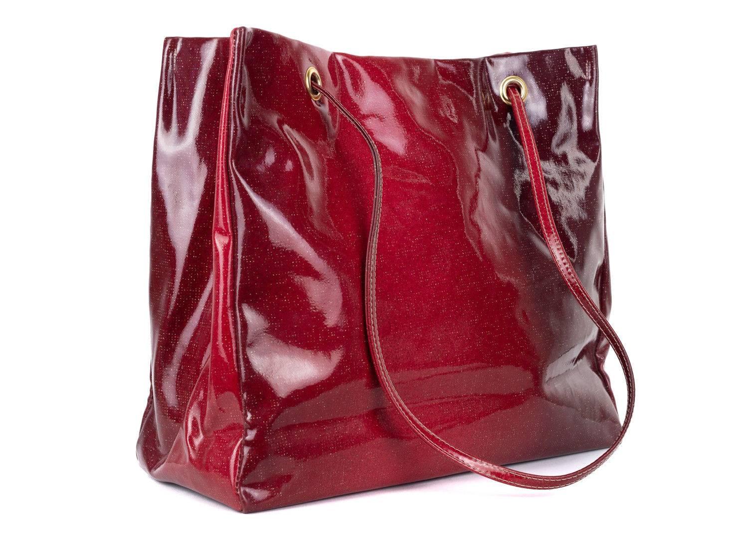 Roberto Cavalli red patent leather tote bag.This large tote bag features a glossy fnish and silver glitter specs with a slgith ombre effect. This large tote bag is perfect to store all your everyday essentials and can be paired with any outfit for a