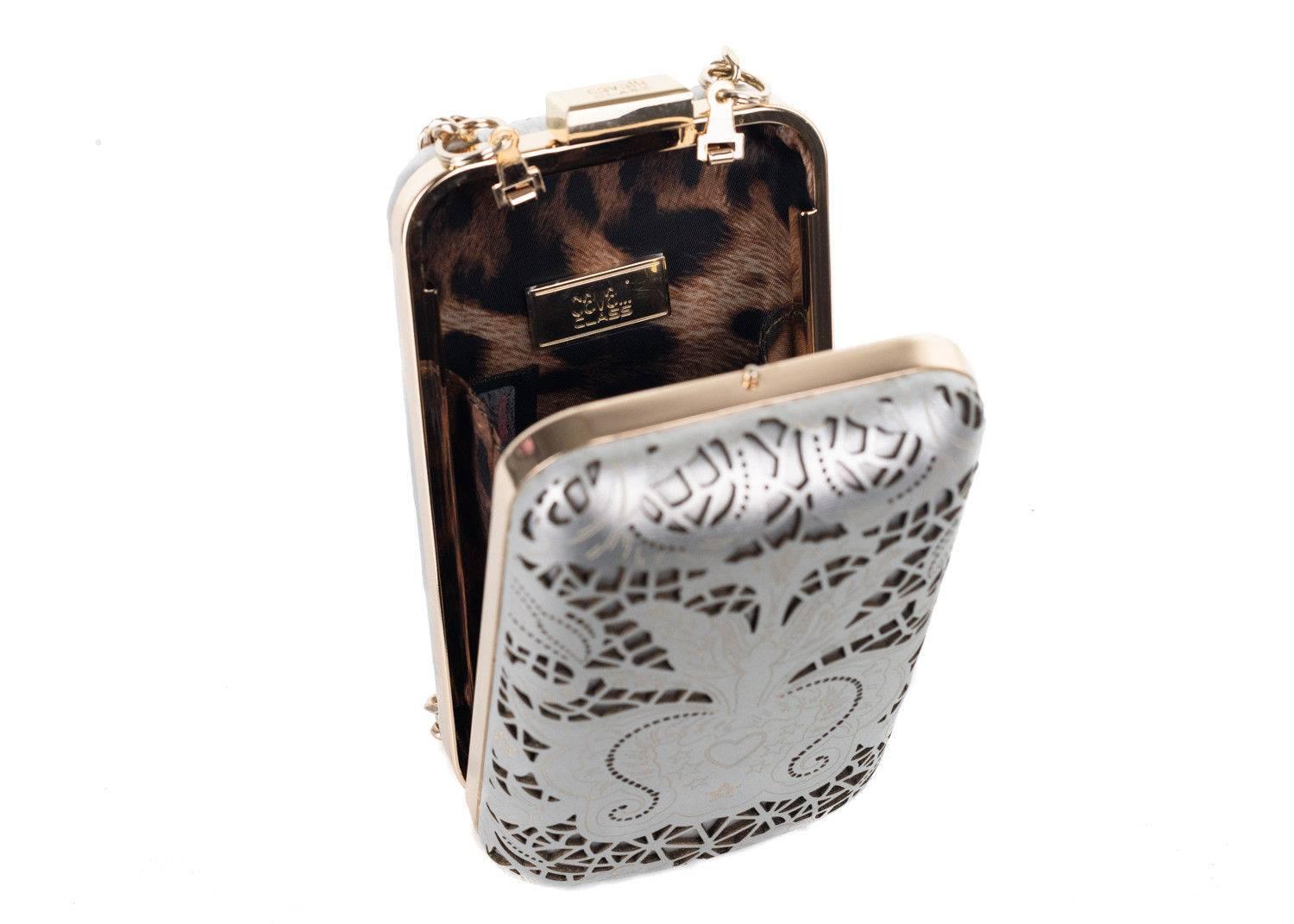 Roberto Cavalli silver metallic clutch. Th clutch features Roberto Cavallis stardust theme with its fun cut out shapes and heart and stars design. This is a fun clutch to wear for evening nights. Spice up your all black ensemble by matching this