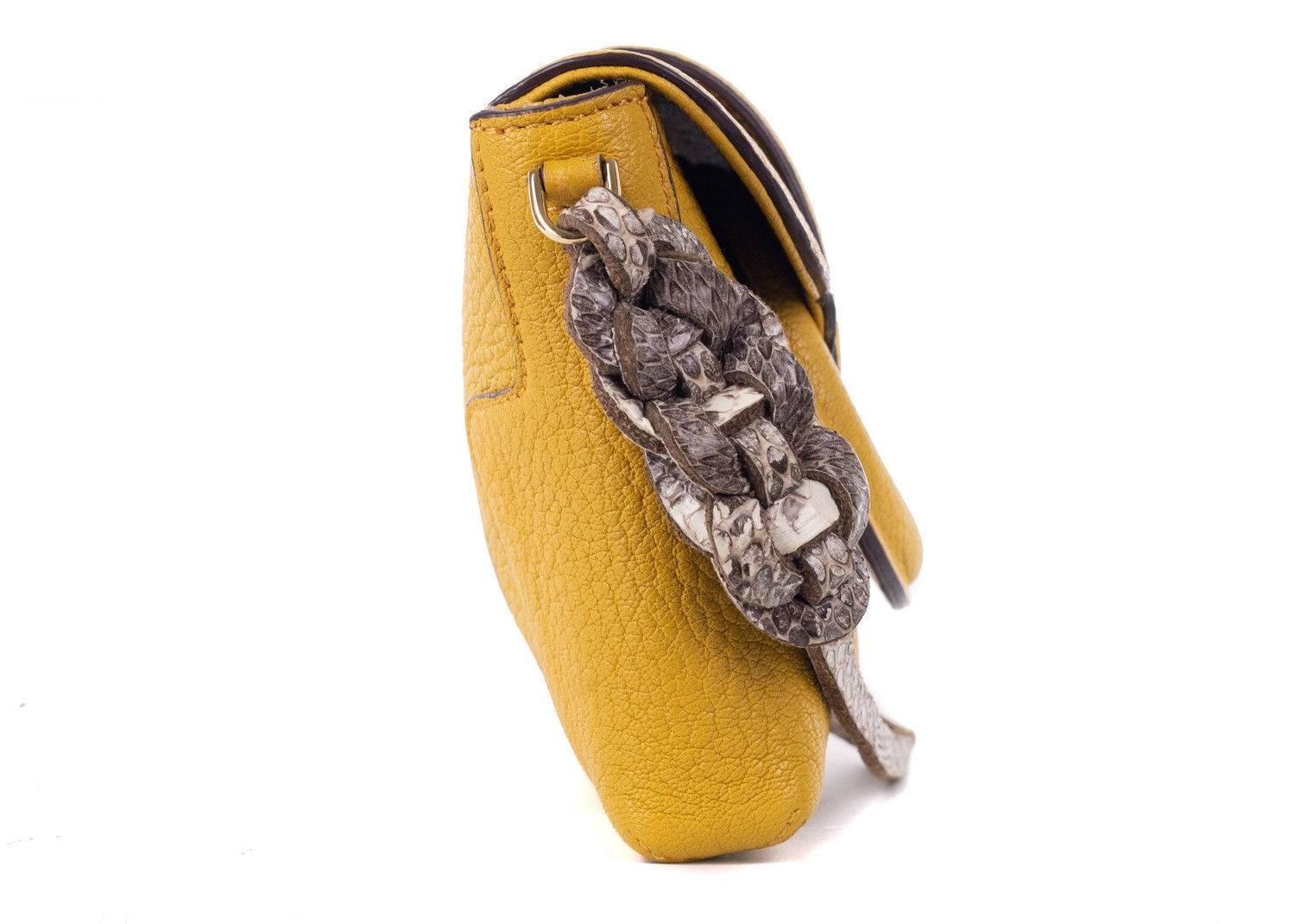 Roberto Cavalli mustard yellow clutch. This clutch features a unique mustard yellow color tone with a snake embossed braided wrsitlet and grained leather textile. Perfect for the incoming summer season, this bag is great to pair with simple denim
