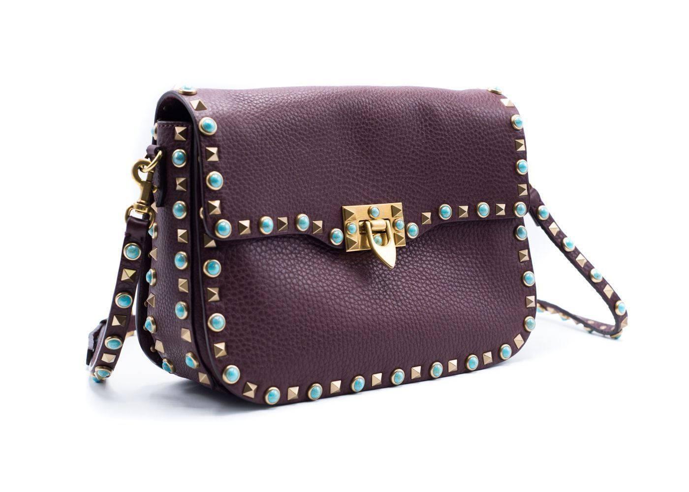 Keep yourself chic with Valentino Garavani's Rockstud Rolling shoulder bag. Crafted from premium textured burgundy leather, this style features the iconic Rockstuds and Rolling turquoise-hued stones for tough-luxe emphasis. Inside, the tri-sectioned