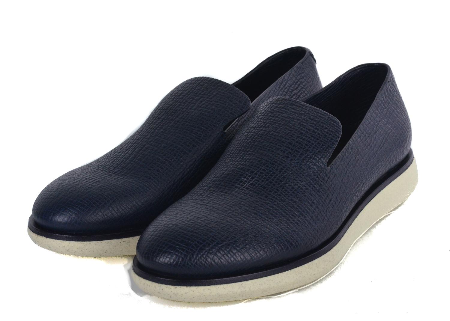 Change the tempo in the room with your Giorgio Armani Slip on Sneakers. These richly textured pair features cross grained striated leather, a deep navy blue color, and firm crisp white rubber sole. This newly reformed loafer style sneaker can be