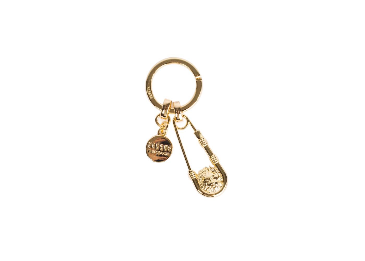 Why play if safe when you can add some edge with your Versus Versace Key Chain. This luxurious unit features a gold safety pin pendant, an encased signature lion head, and classic Versus Versace logo pendant. You can tastefully pin your essentials