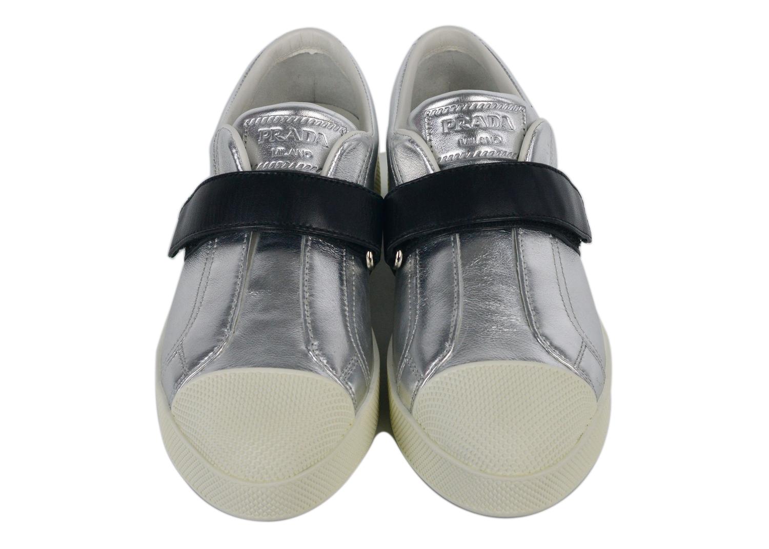 Incredible silver leather sneakers from Prada featuring a round rubber toe,  a brand embossed insole, a hook and loop style and a rubber sole. Prada takes the classic low-top design and gives it a contemporary revamp with this pair of white textured