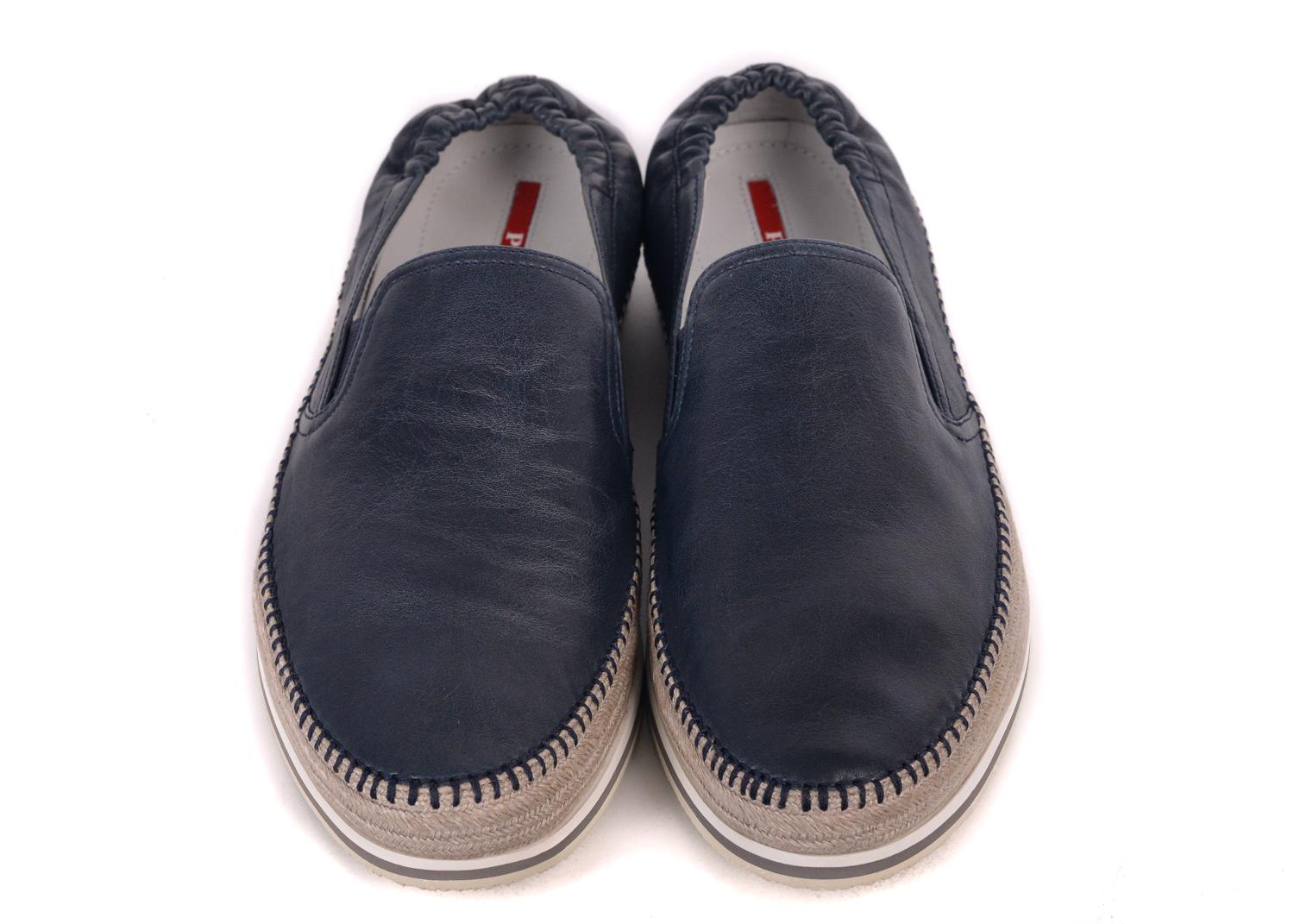 Prada reintroduces the navy leather loafers with this unconventional wonder, leather upper, braided  sidewall  and rubber sole.  You can pair this shoe with a aerated linen outfit for the perfect summer appeal.

Leather
Braided sidewall
Rubber