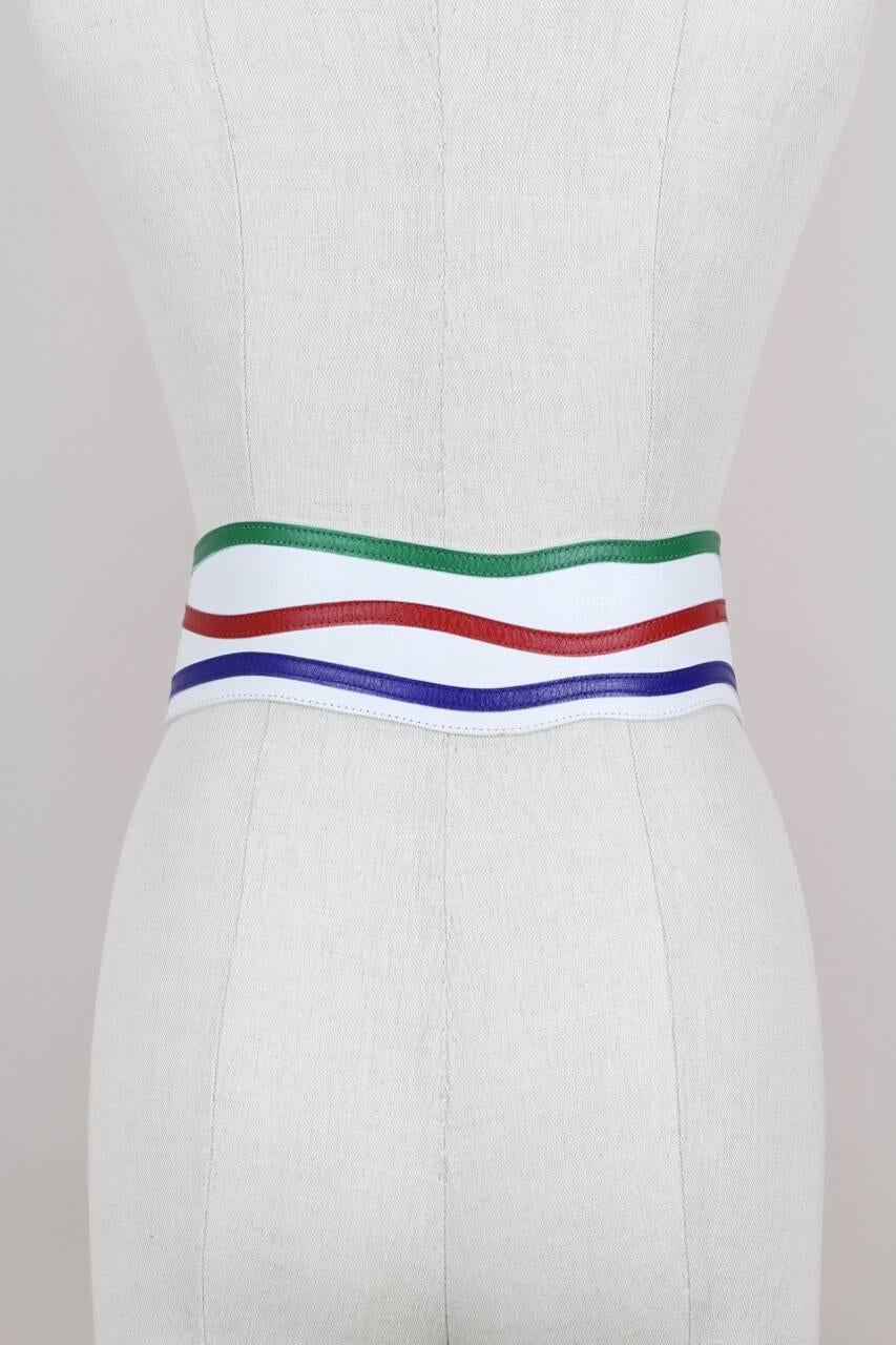 This Yves Saint Laurent wave-shaped wide leather belt is made from white slightly structured smooth leather and features an oversized asymmetrical cherry-red leather covered buckle and thin appliquéd leather bands in bottle-green, cherry-red and